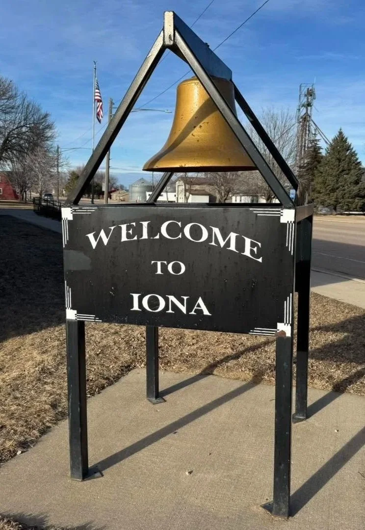 Welcome sign for Iona with a large yellow bell above it.