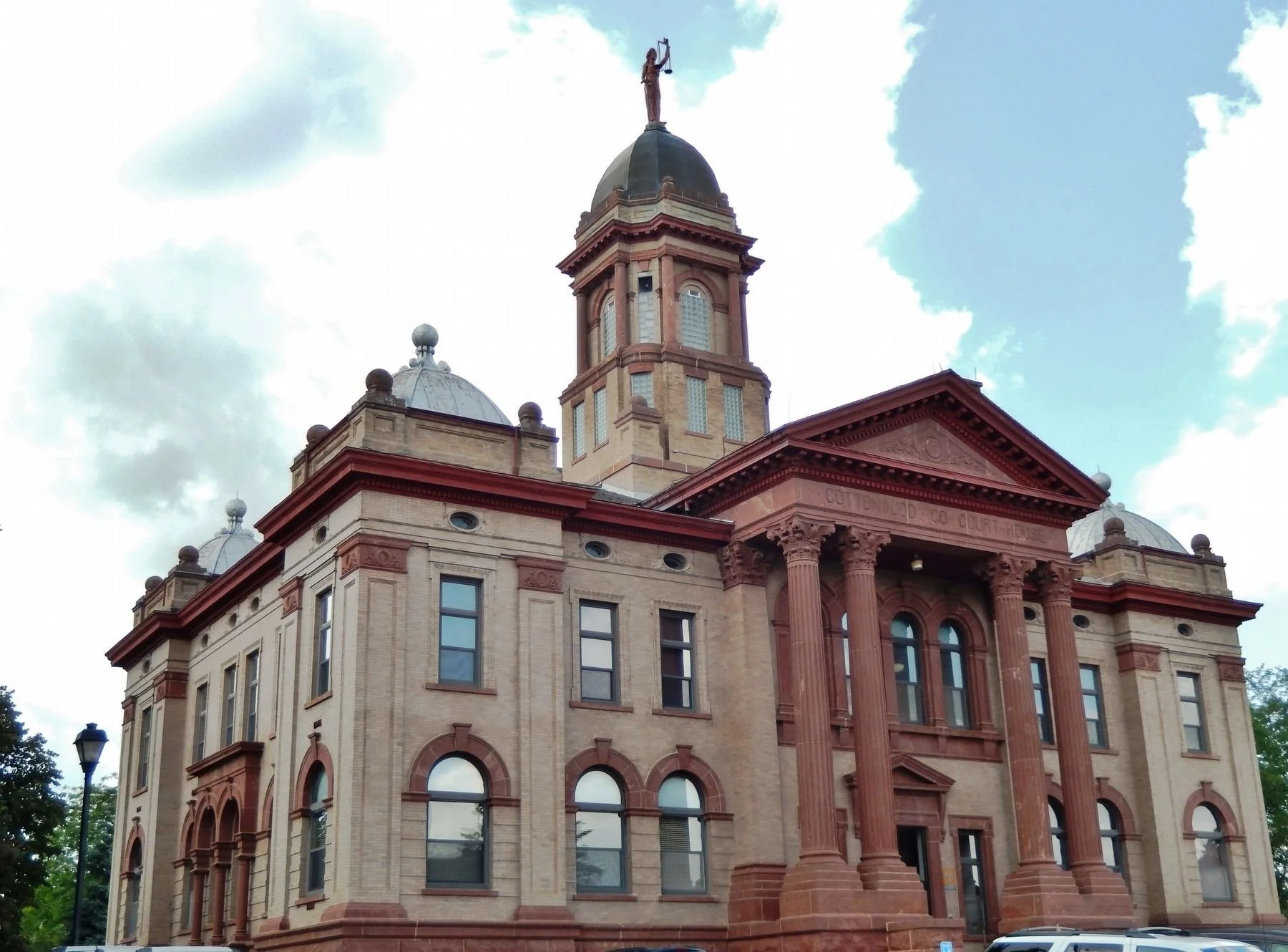 Historic courthouse building with a dome and clock tower, featuring columns at the entrance and decorative architectural details, under a cloudy sky.