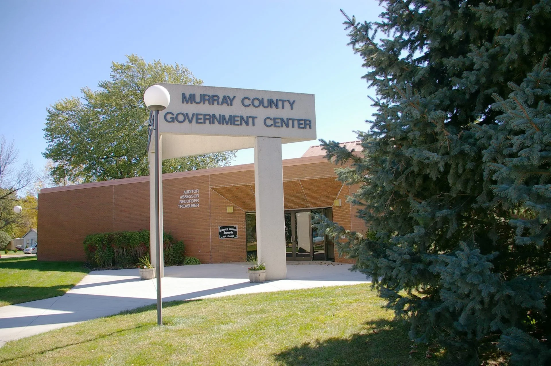 Murray County Government Center sign in front of a brick building with trees and a lawn.
