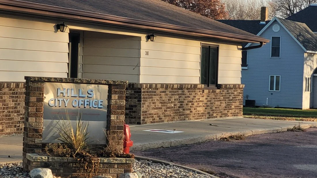 The Hills City Office building with a brick and siding exterior, and a sign that reads 'Hills City Office' in front.