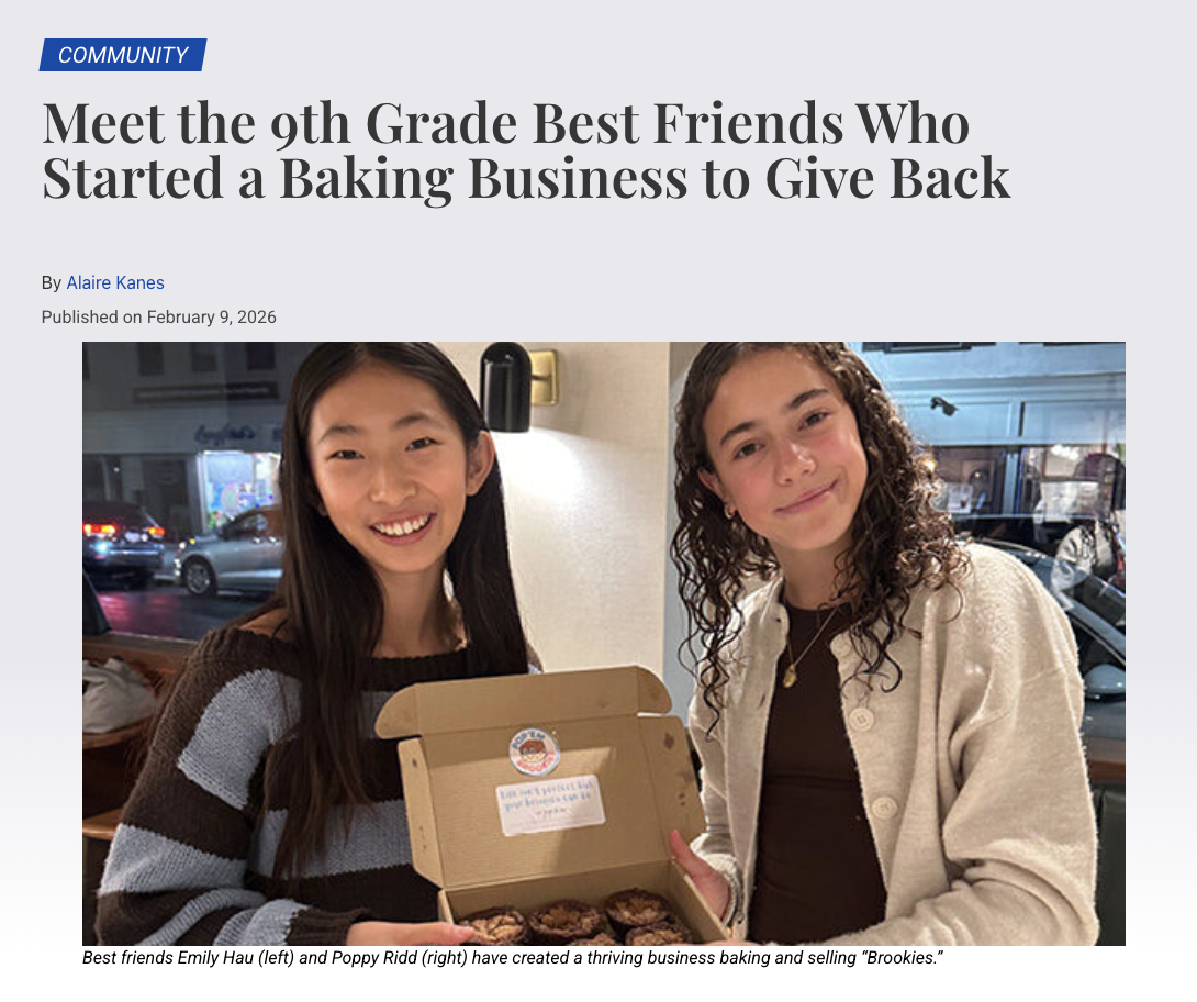 Two young women, Emily Hau and Poppy Ridd, smiling and holding a cute packaging box of baked brookies.