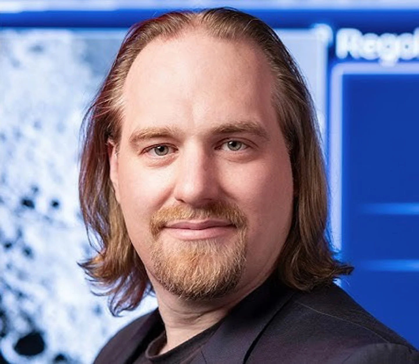 Prof. Stephan Jacob, Professor für Creative Technology an der Hochschule Darmstadt und Experte für Games, KI und Gamification, vor blauem Hintergrund.
