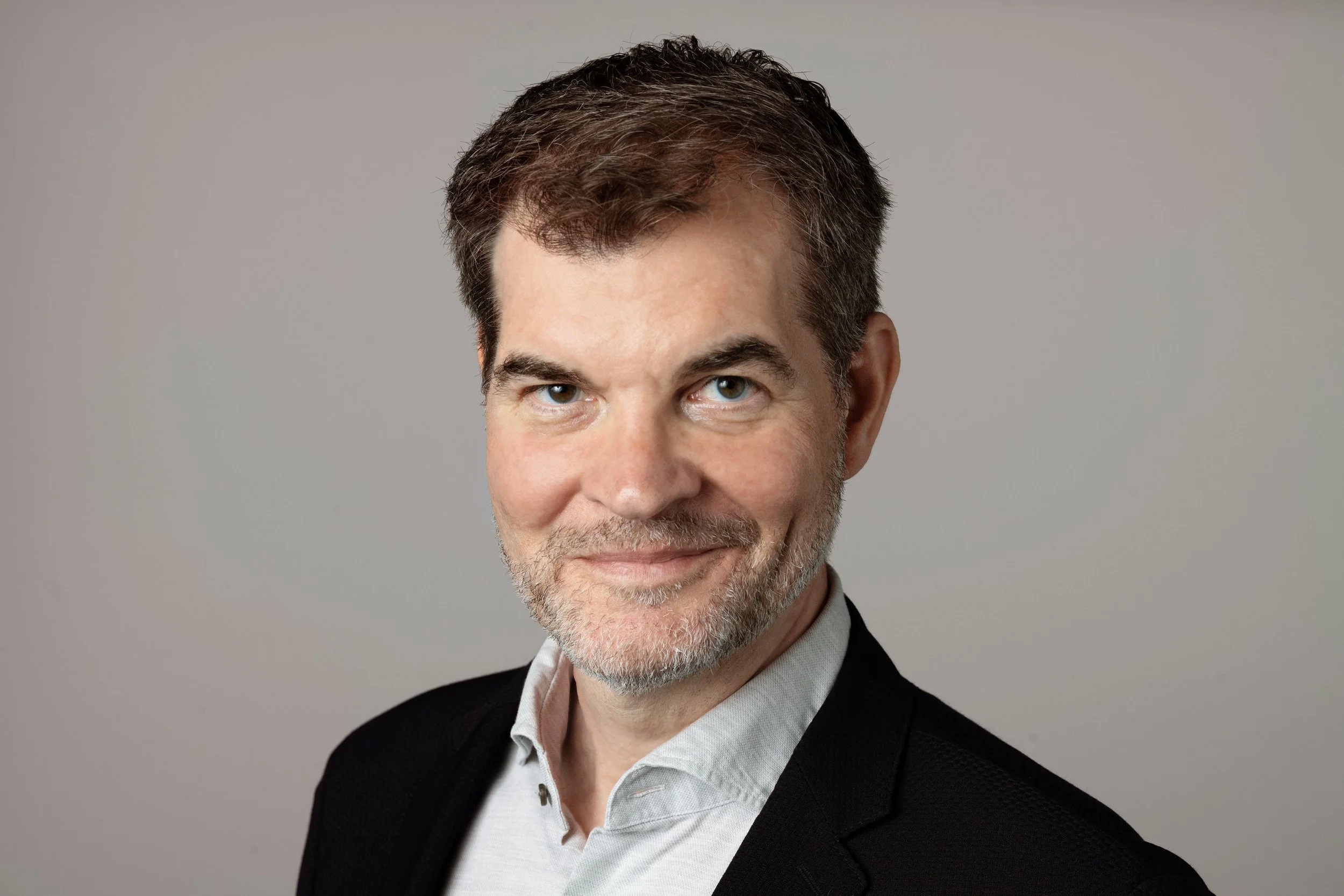 Holger Windfuhr, Art Director der Frankfurter Allgemeinen Zeitung (FAZ) und Mitglied des Art Directors Club, im schwarzen Anzug vor neutralem Hintergrund.