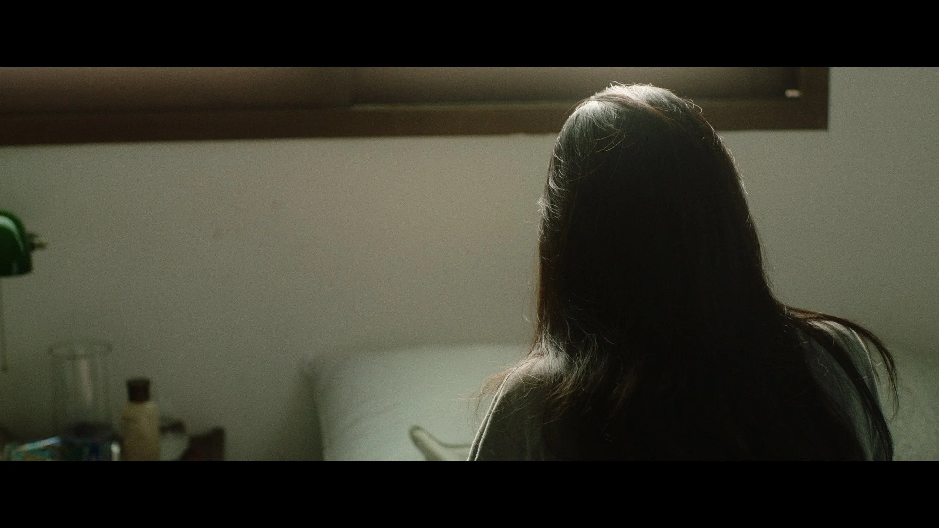 A woman with long dark hair sitting at a table in a dimly lit room.