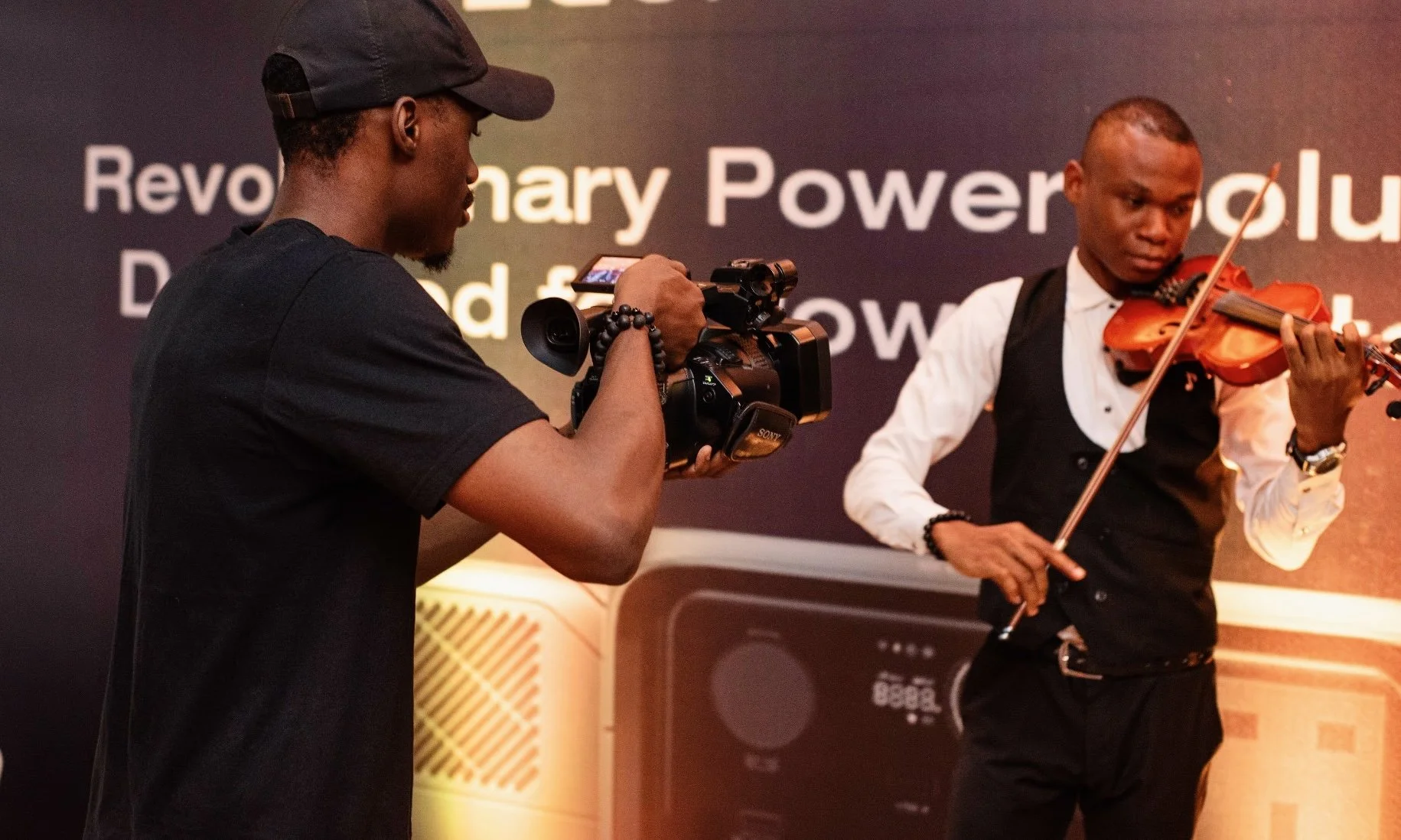 Camera operator filming a violin performance during the EcoFlow corporate event.
