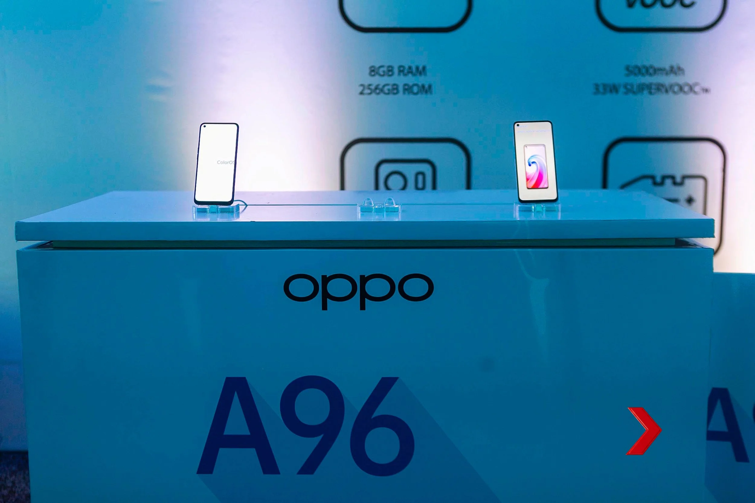 Display of two smartphones on a table, with specifications written behind them, including 8GB RAM and 256GB ROM, on a blue background with the OPPO logo.