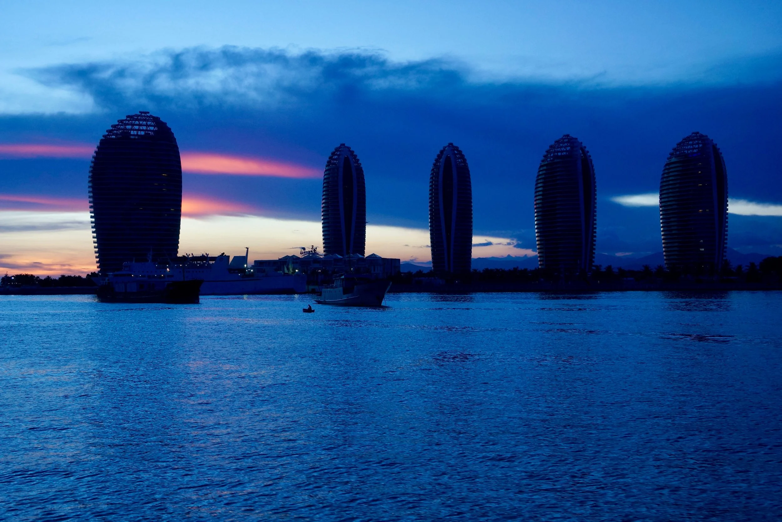 Phoenix Island Resort Sanya (三亚凤凰岛度假酒店) silhouetted against a deep blue evening sky.