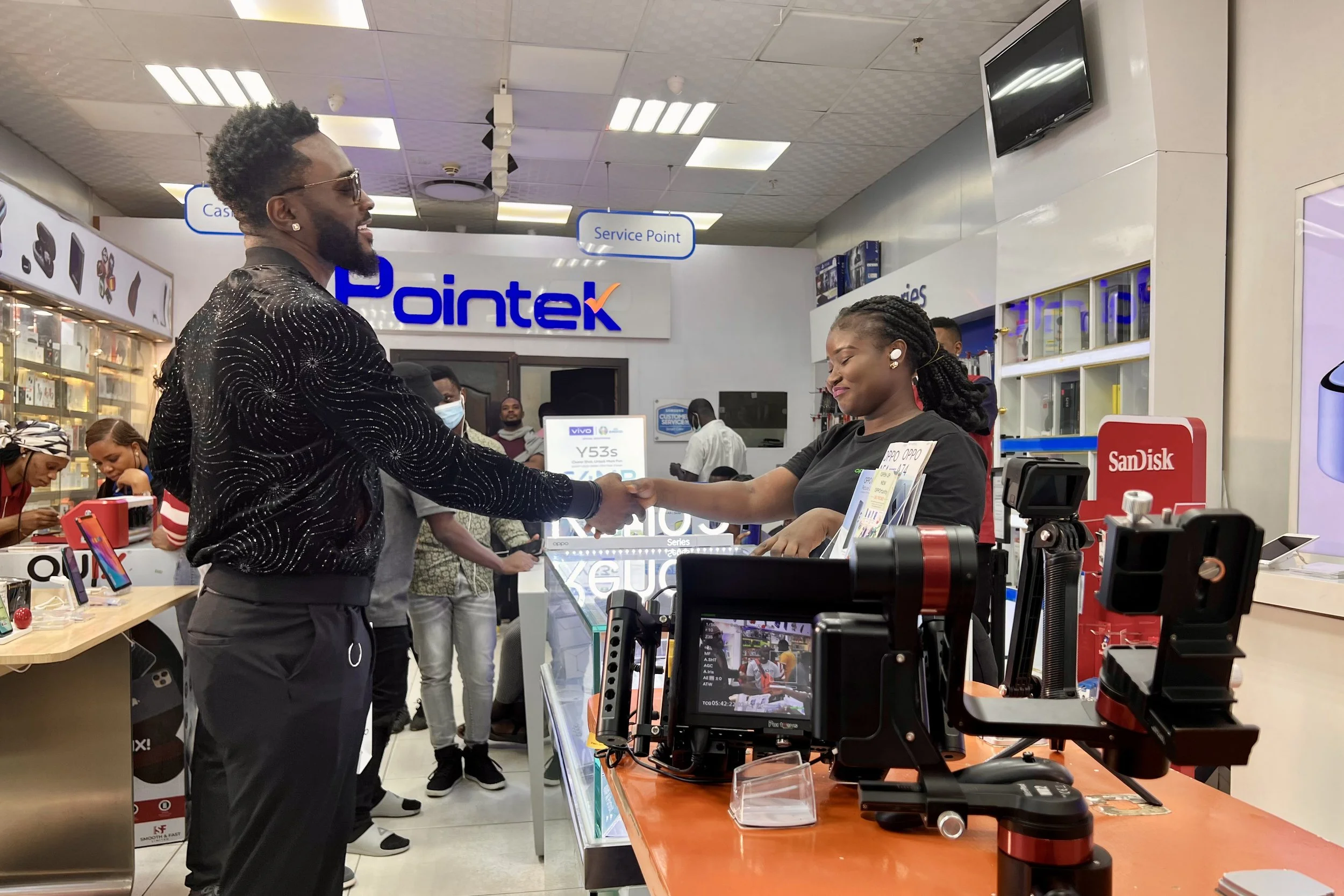 Actors shaking hands at store counter inside a retail electronics store during a video shoot