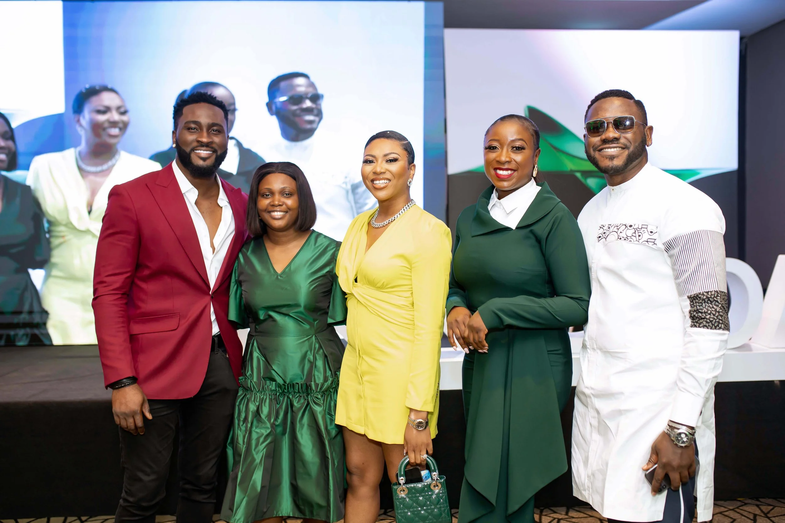 Six well-dressed guest standing together in front of a large, bright digital screen at an indoor OPPO event, smiling for the camera.