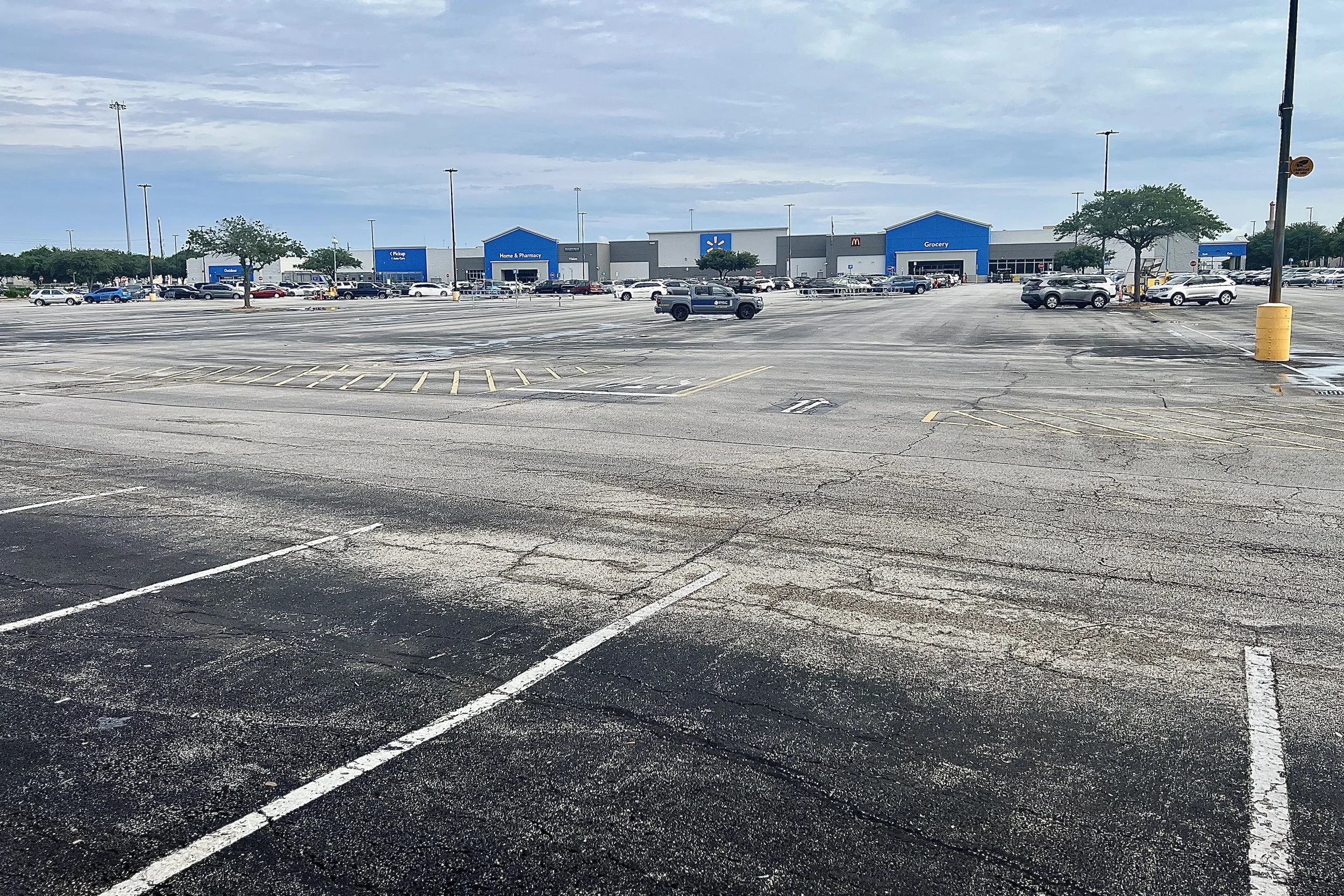 A massive, mostly empty parking lot stretching toward a distant Walmart Supercenter.