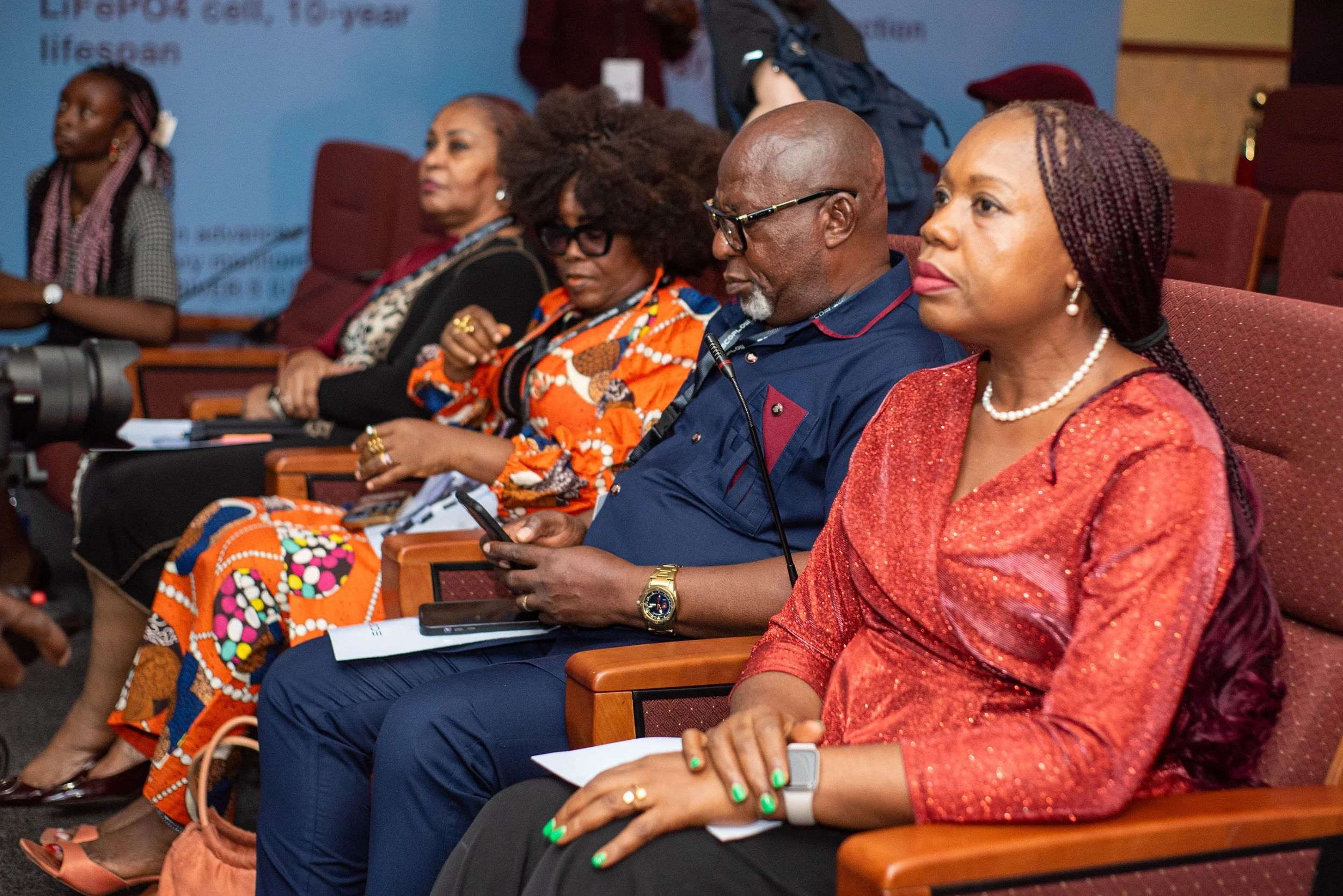 A diverse group of people attending an EcoFlow event, seated in red chairs, listening attentively.