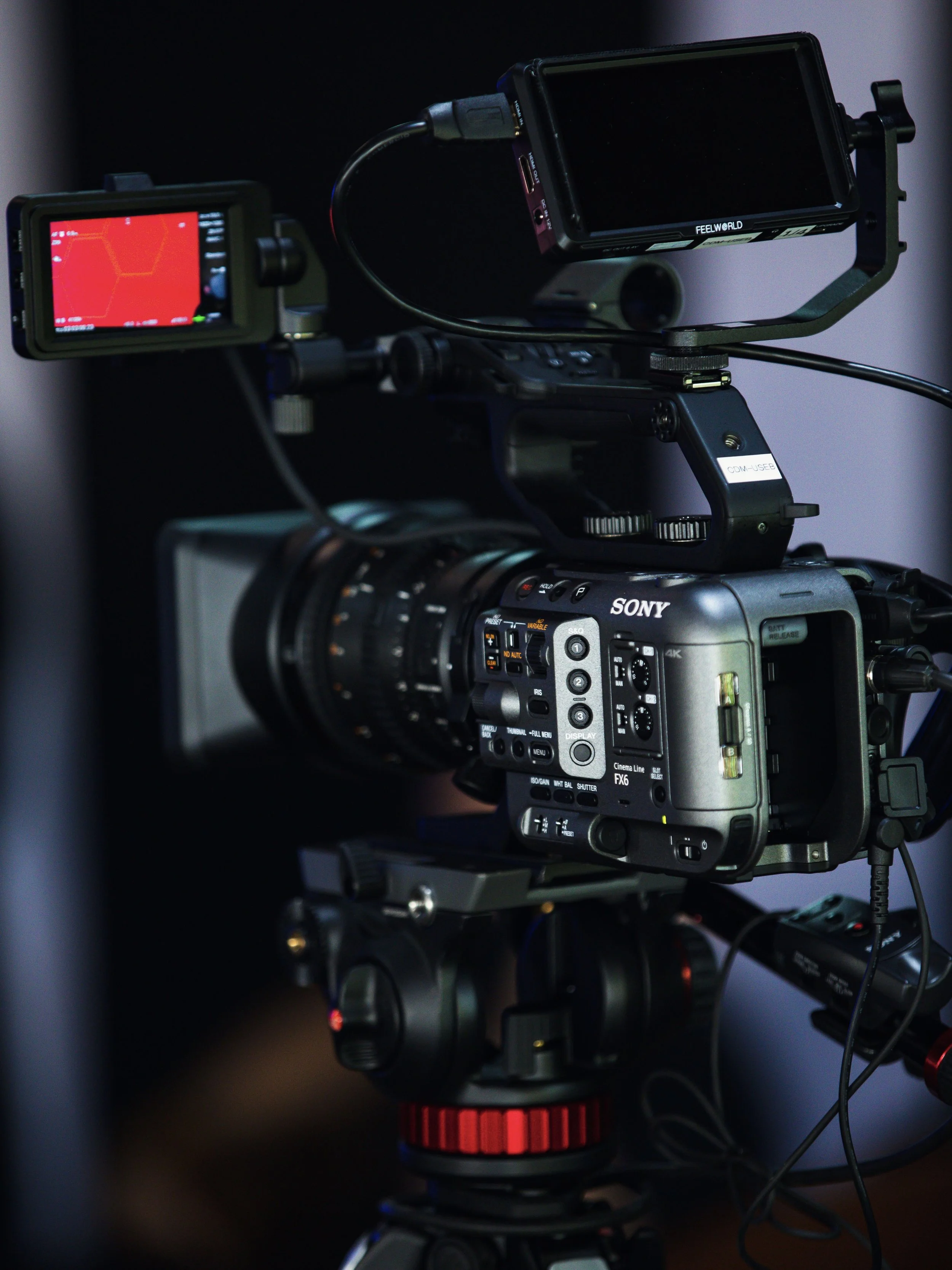 Close-up of a Sony digital cinema camera on a tripod, with two monitor screens attached, used for professional filming.
