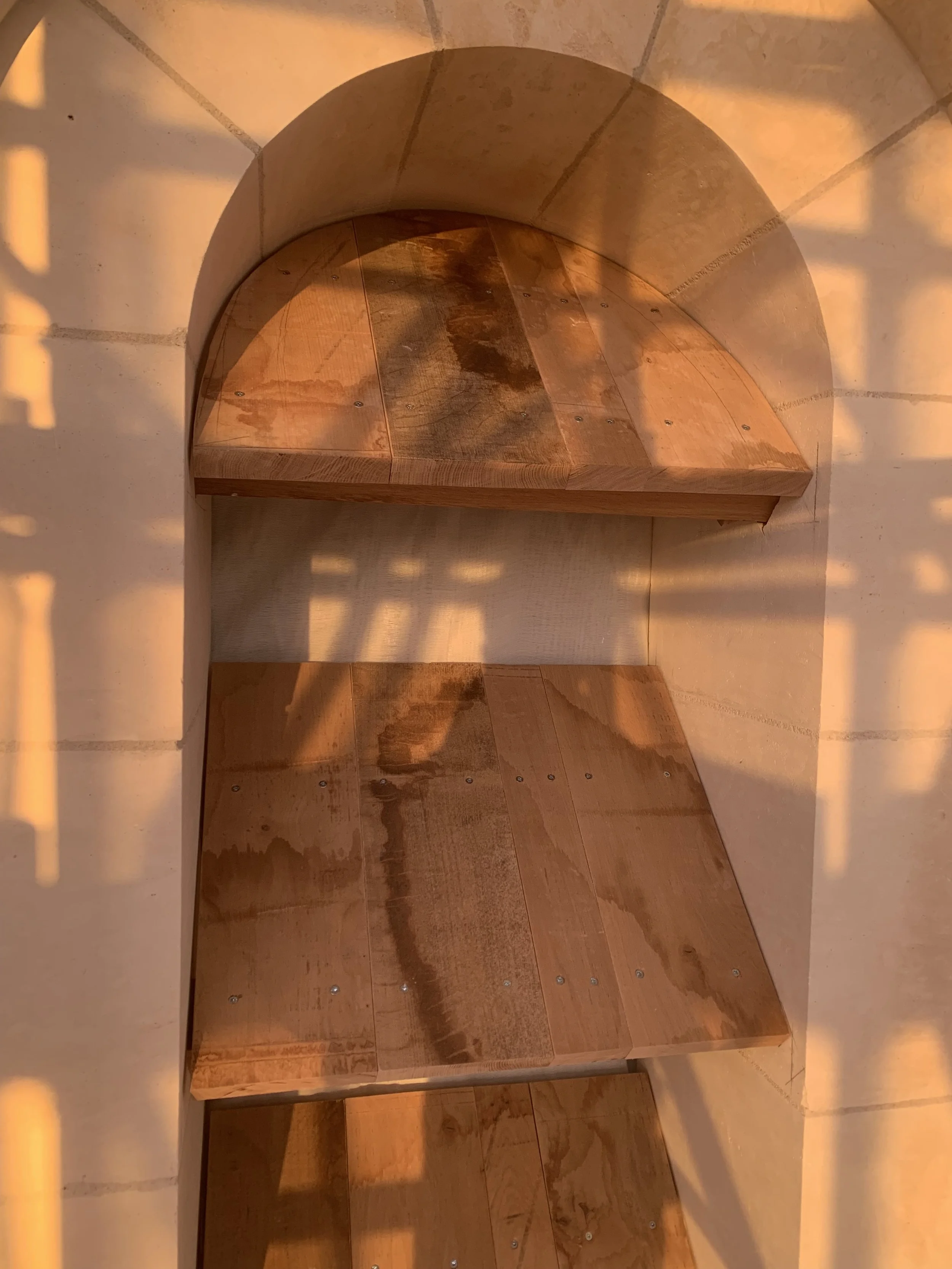 Un escalier en bois dans une structure en pierre avec un éclairage chaud.