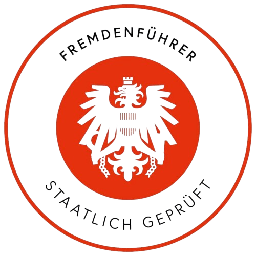 A circular emblem featuring a blue eagle with outstretched wings, a red background behind the eagle, and black text around the border that reads 'Fremdenführer' at the top and 'Sichtlich geprüft' at the bottom.