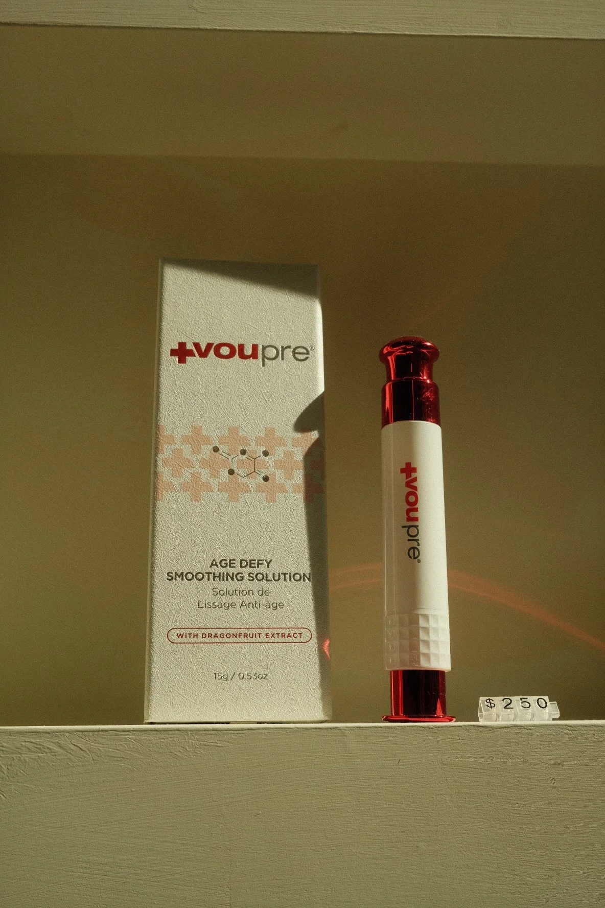 A skincare product called 'Age Defy Smoothing Solution' with dragonfruit extract, displayed next to a pen-shaped container with a red and white design, priced at $2.50.