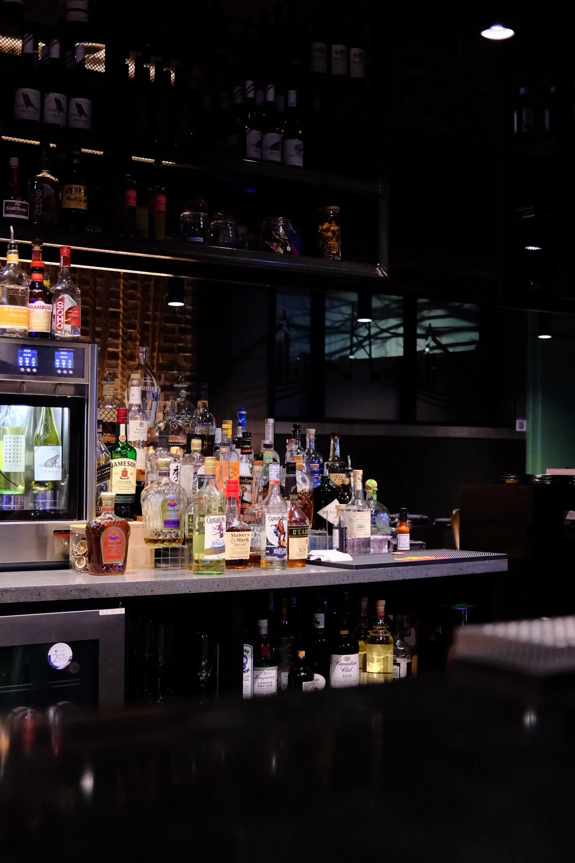 Bar with various liquor bottles on the counter and shelves, dim lighting, and a dark ambiance.