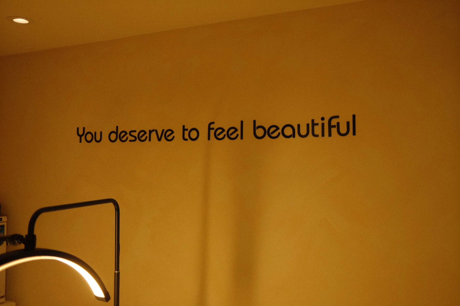 A motivational quote on a yellow wall that reads, 'You deserve to feel beautiful.'