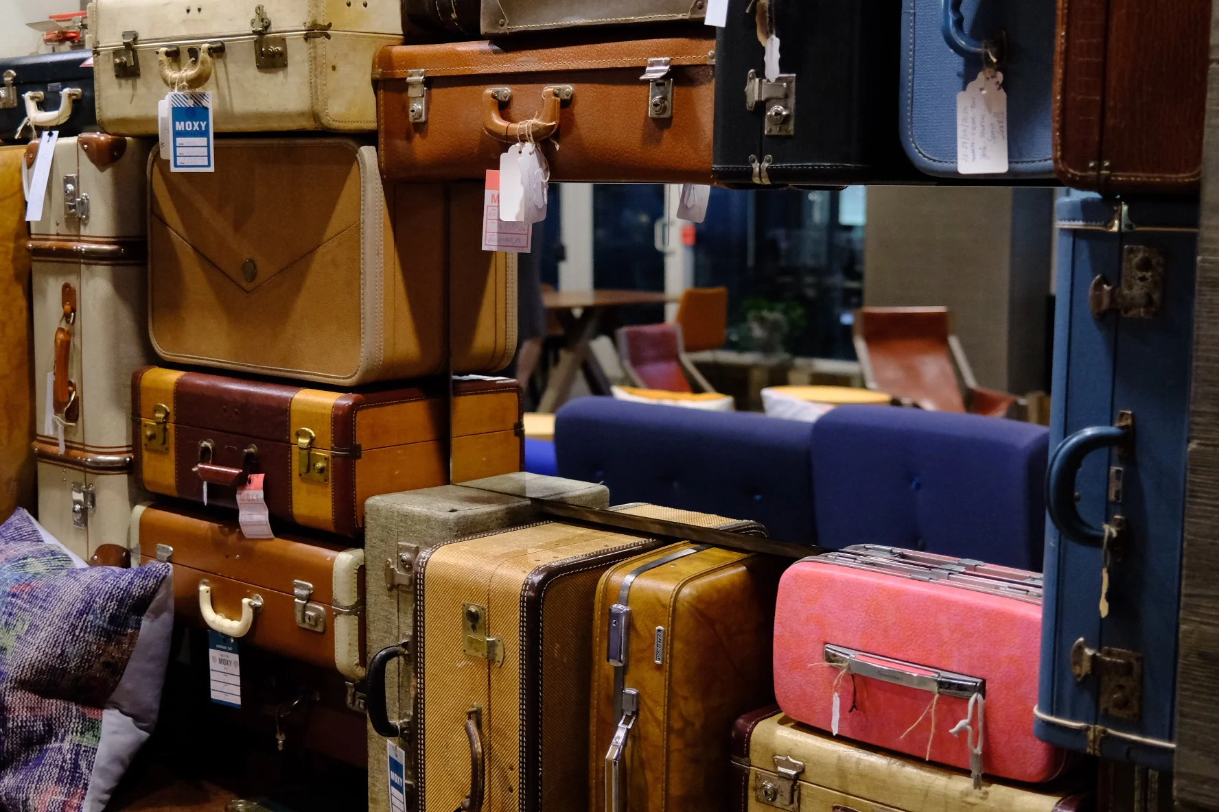 A display of vintage suitcases and briefcases in various colors and sizes on a shelf at a store.