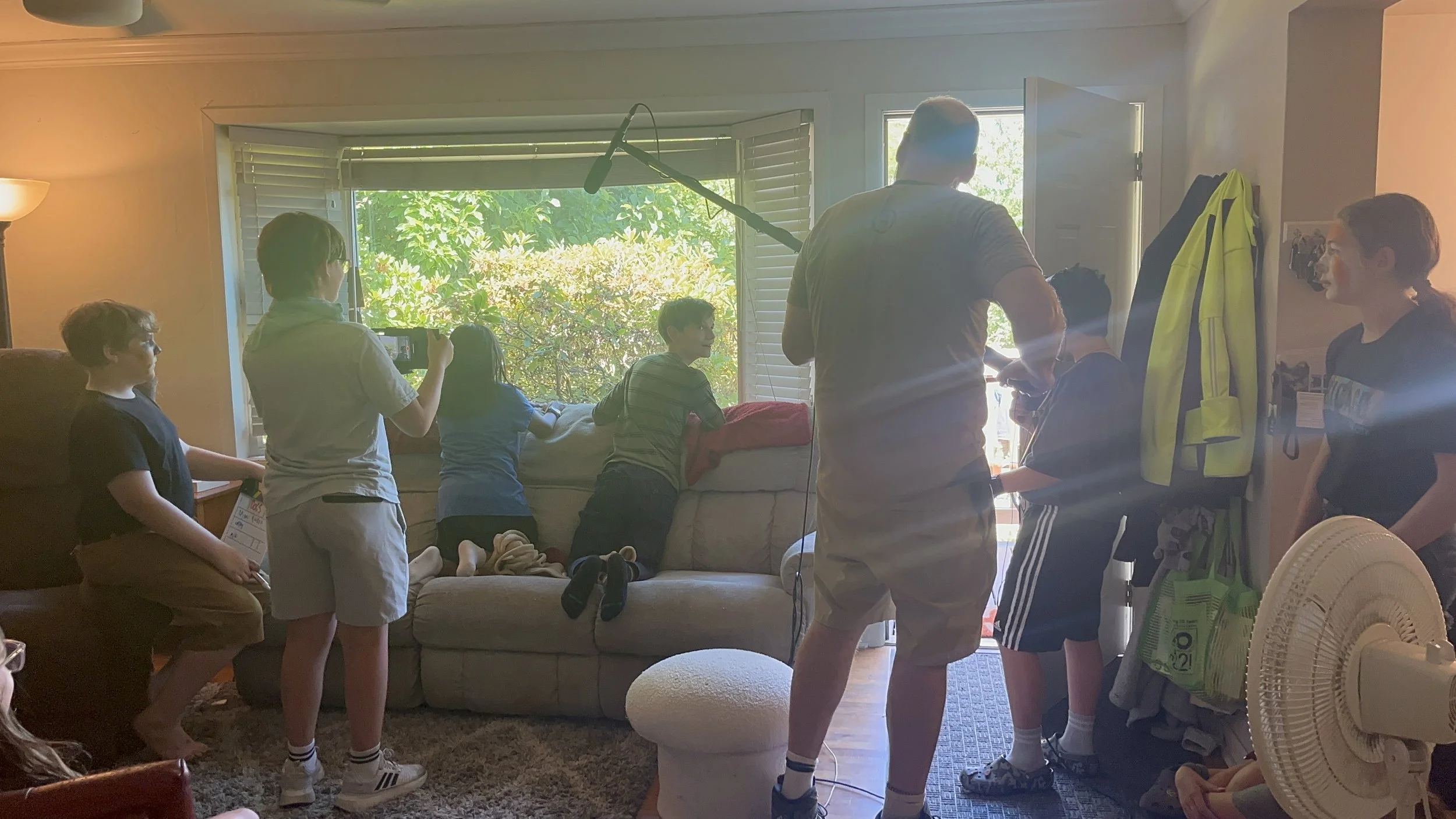 Wayne Rawley holding a boom mic surrounded by students learning filmmaking at an annual neighborhood film camp.