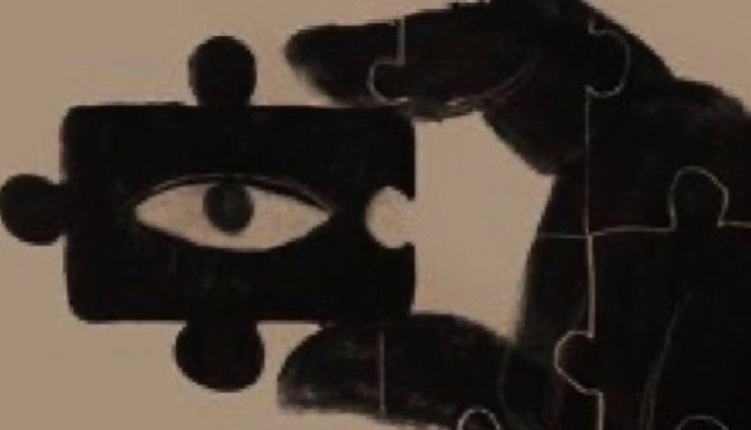 A hand holding a black jigsaw puzzle piece with an eye symbol cut out, against a beige background.
