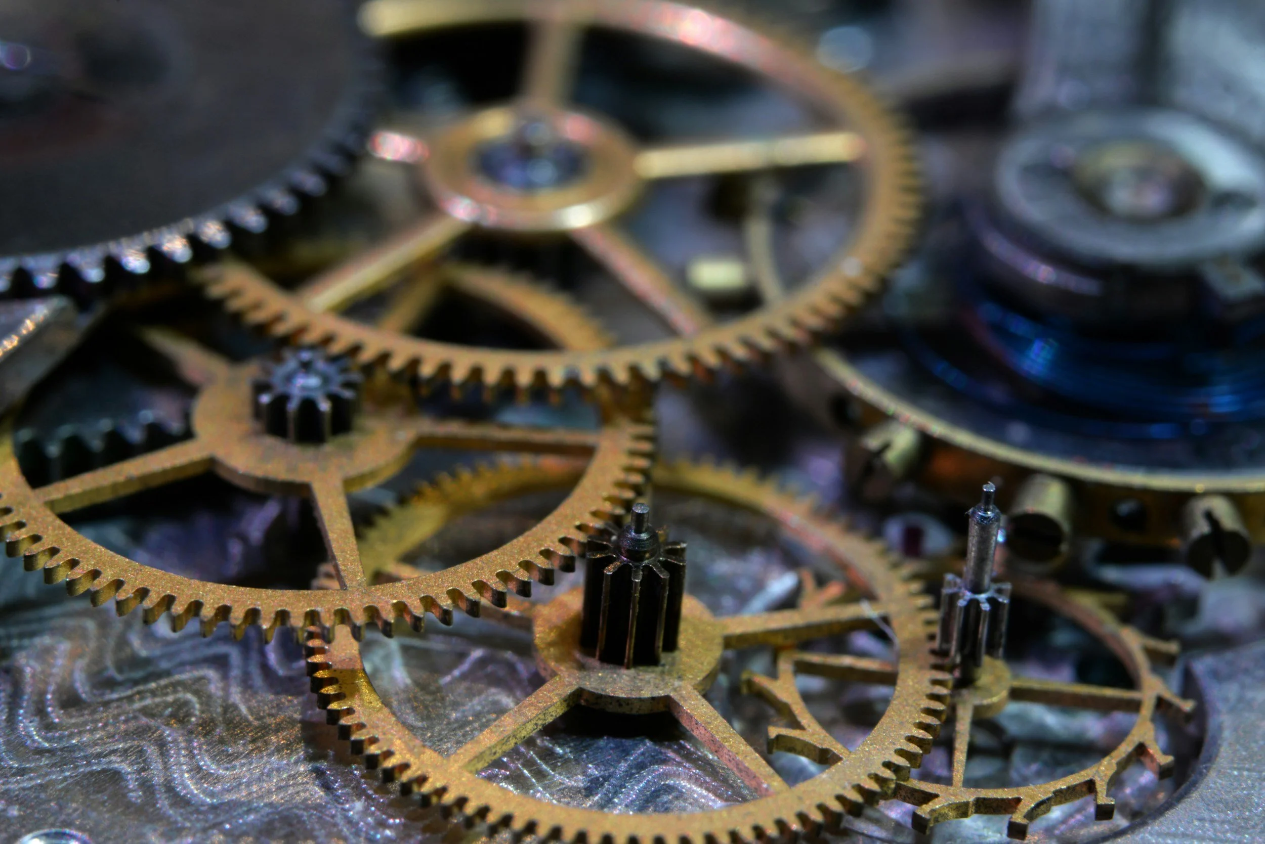 Close-up view of interconnected brass gears and cogs, some partially visible, on a metallic background.