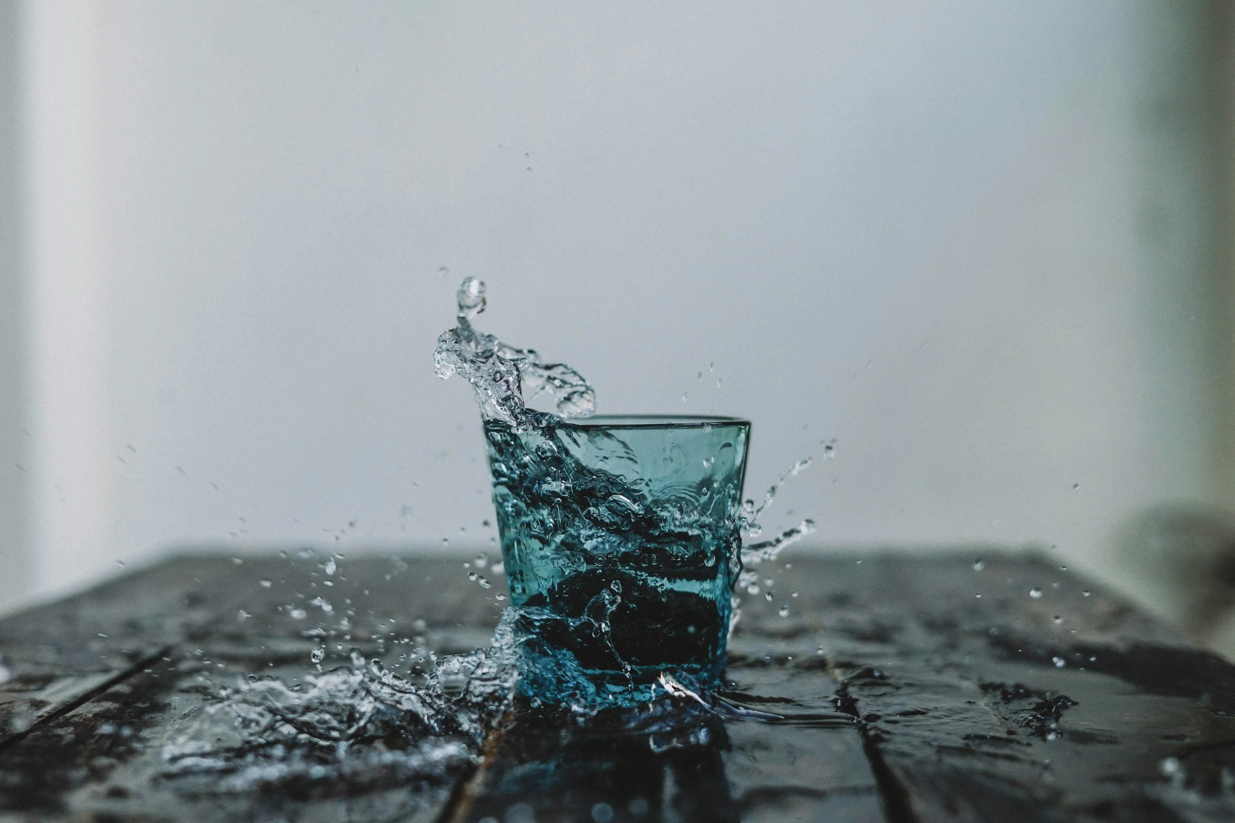 A splash of water in a clear glass with a plain background.