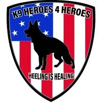 A shield-shaped emblem with a black silhouette of a German Shepherd dog, blue and red vertical stripes, and text that says 'K9 Heroes 4 Heroes' at the top and 'Healing is Healing' at the bottom.