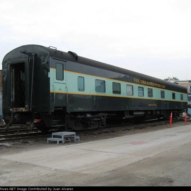 A two-toned green rail cal called the Chestnut Hill sits in a rail yard