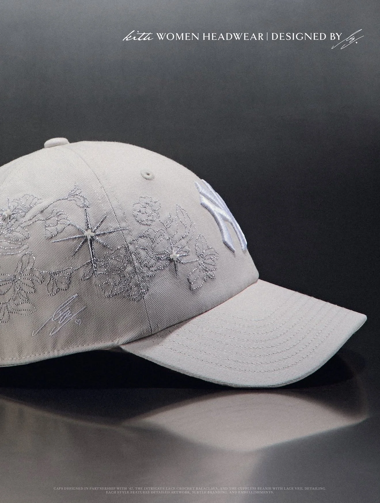 A beige baseball cap embroidered with floral designs and signatures, positioned against a dark background with white text at the top.