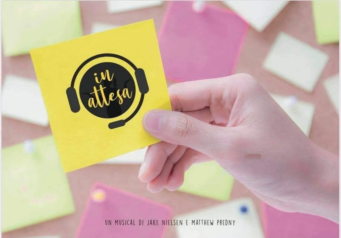 A hand holding a yellow sticky note with a black graphic of headphones and the text 'in attesa' in yellow, surrounded by colorful sticky notes on a surface.