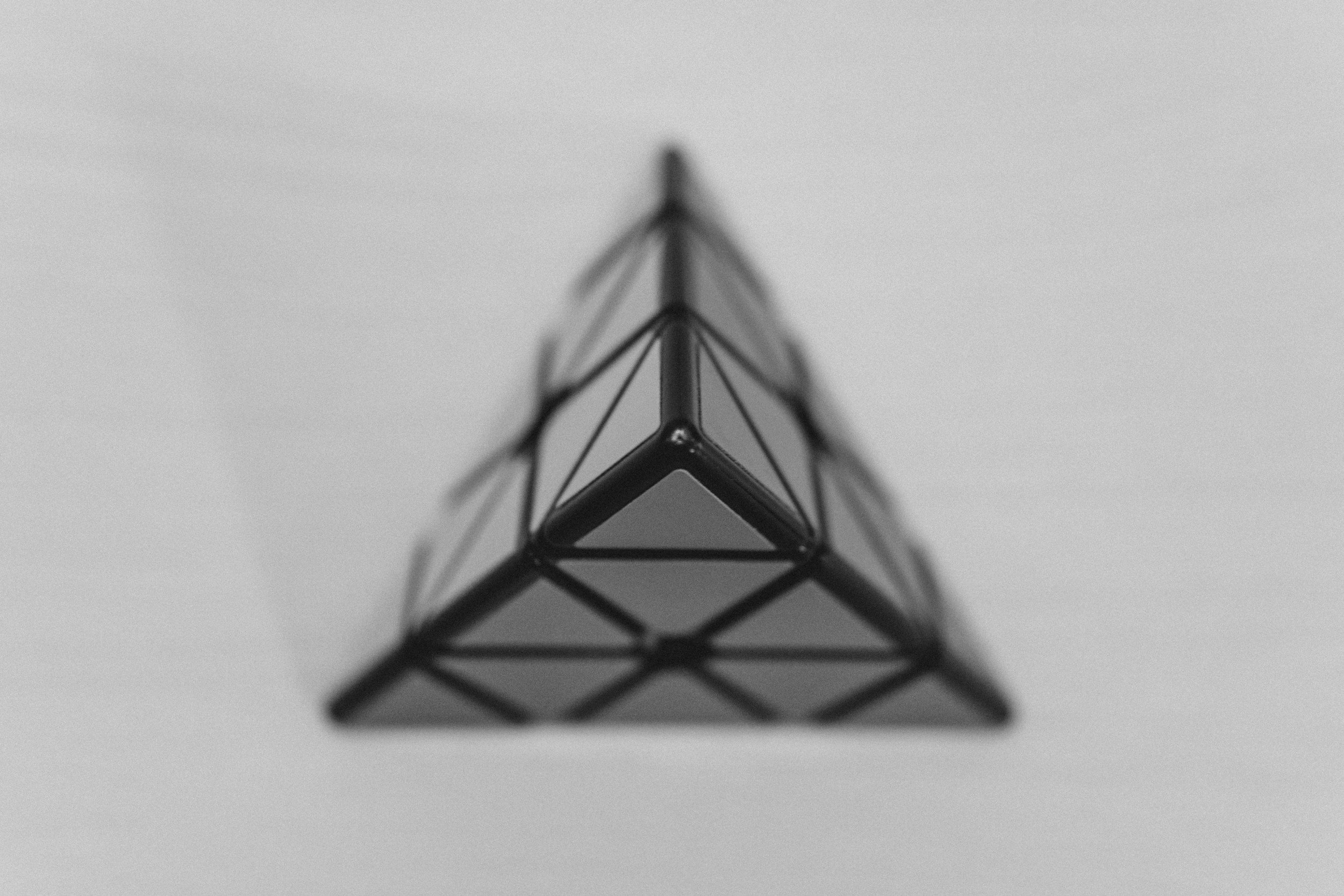 Close-up of a wireframe model of a triangular structure, viewed from the front with a blurred background.