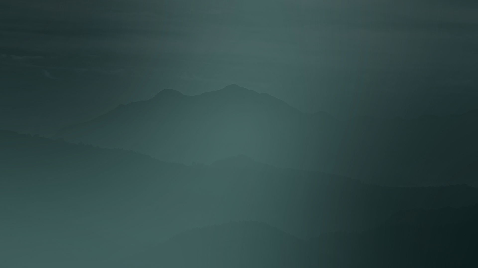 Mountain range with layered silhouettes under cloudy sky