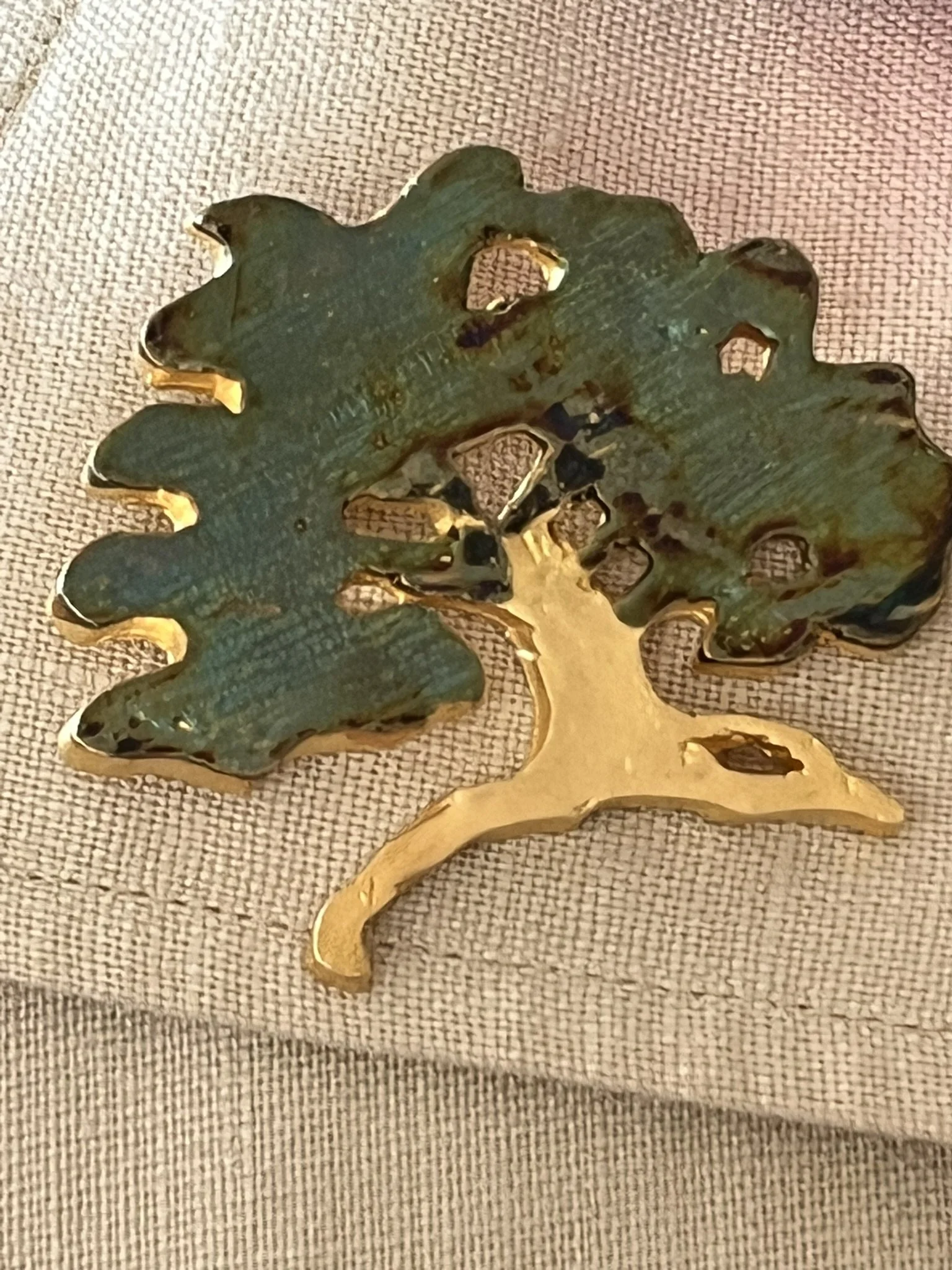 Gold Tone Tree Brooch Laying on Cream Linen Lapel