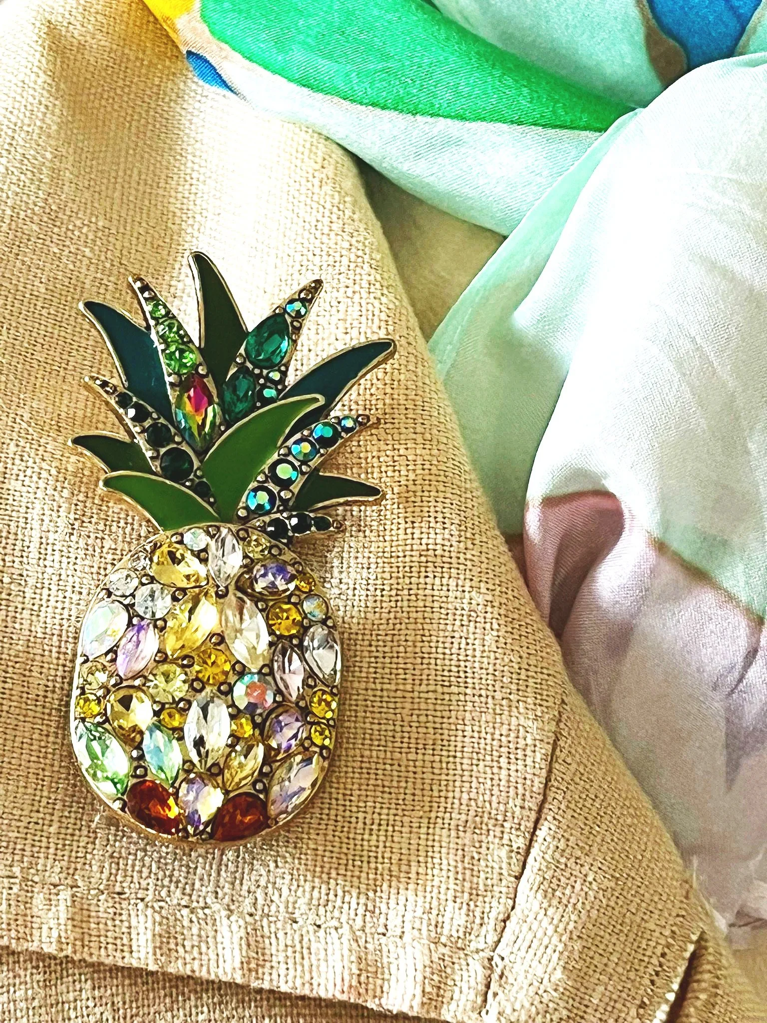 Shop this stunning tropical pineapple brooch featuring multi-color sparkling rhinestones and vibrant green enamel leaves. The perfect gold-tone statement pin for blazers and scarves.