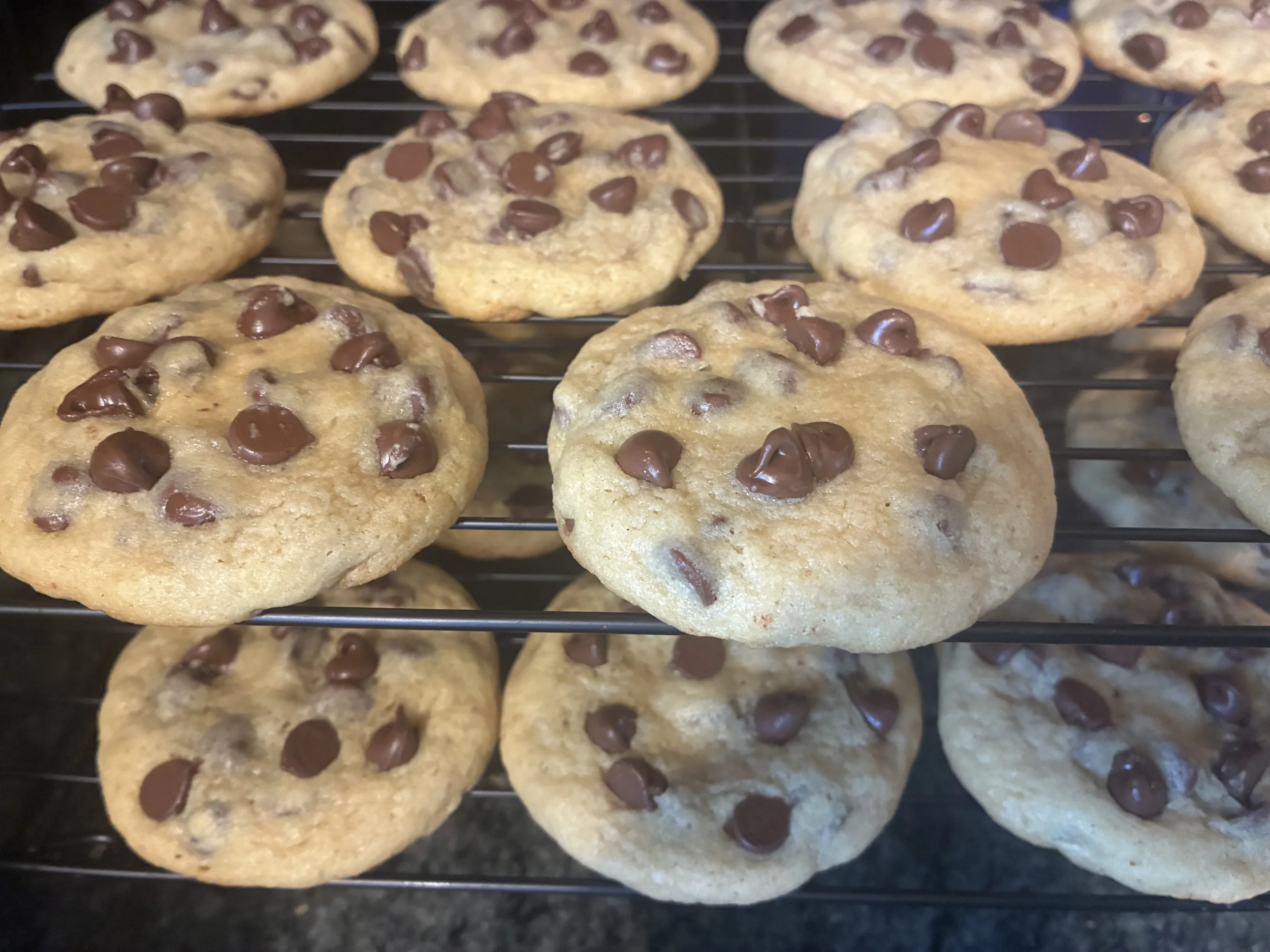 Close-up of freshly baked chocolate chip cookies on a wire cooling rack.