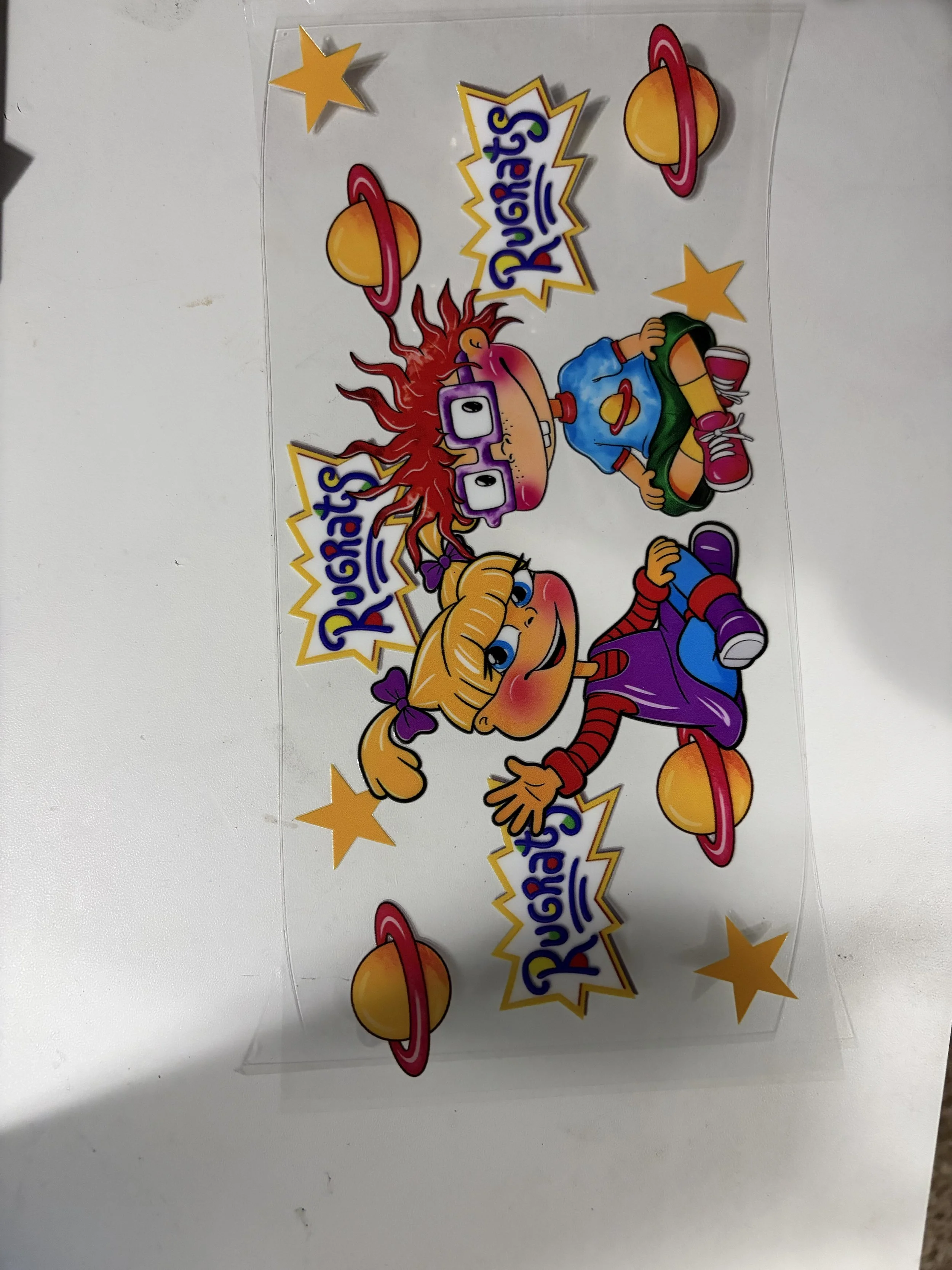Colorful sticker featuring cartoon children, planets with rings, and stars, with the text 'Duggi's Rockets'.