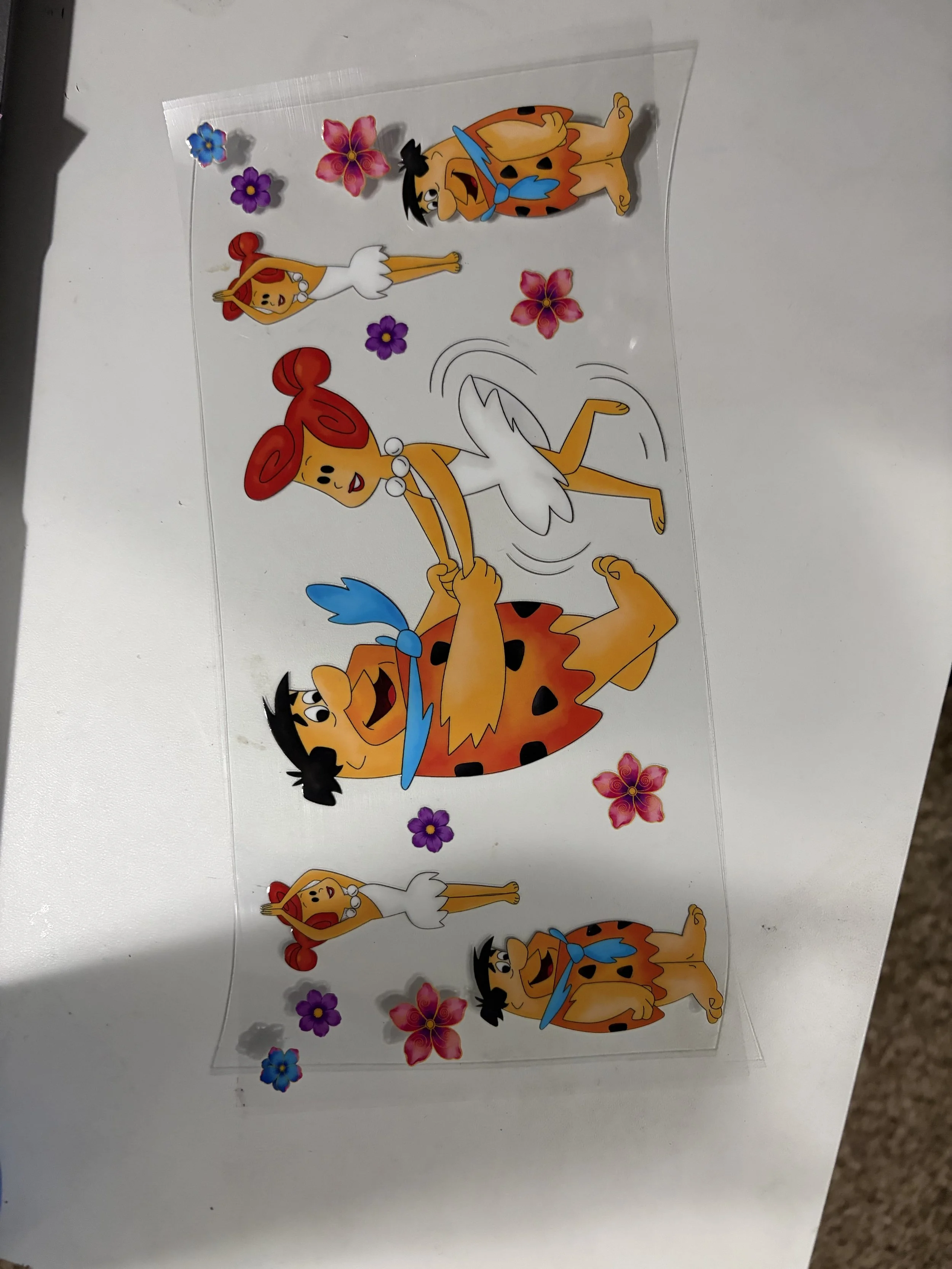 Decorative sticker sheet featuring animated characters from The Flintstones, including Fred Flintstone and Wilma Flintstone, surrounded by colorful flowers.