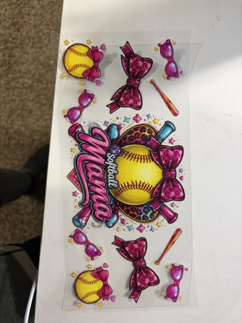 A sticker sheet themed around softball, featuring a large yellow softball with pink bows and smaller softball stickers, pink and blue bat stickers, and pink sunglasses stickers.