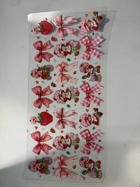 Sheet of Christmas-themed stickers featuring bows, Christmas trees, and Santa Claus figures.