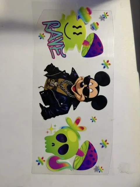 Colorful Disney-themed stickers featuring Mickey Mouse dressed in black with glasses and chains, and ghost-like characters with rainbow-colored mushroom hats, surrounded by small multicolored flower-like shapes, with the word "RAVE" and a smiling green face.