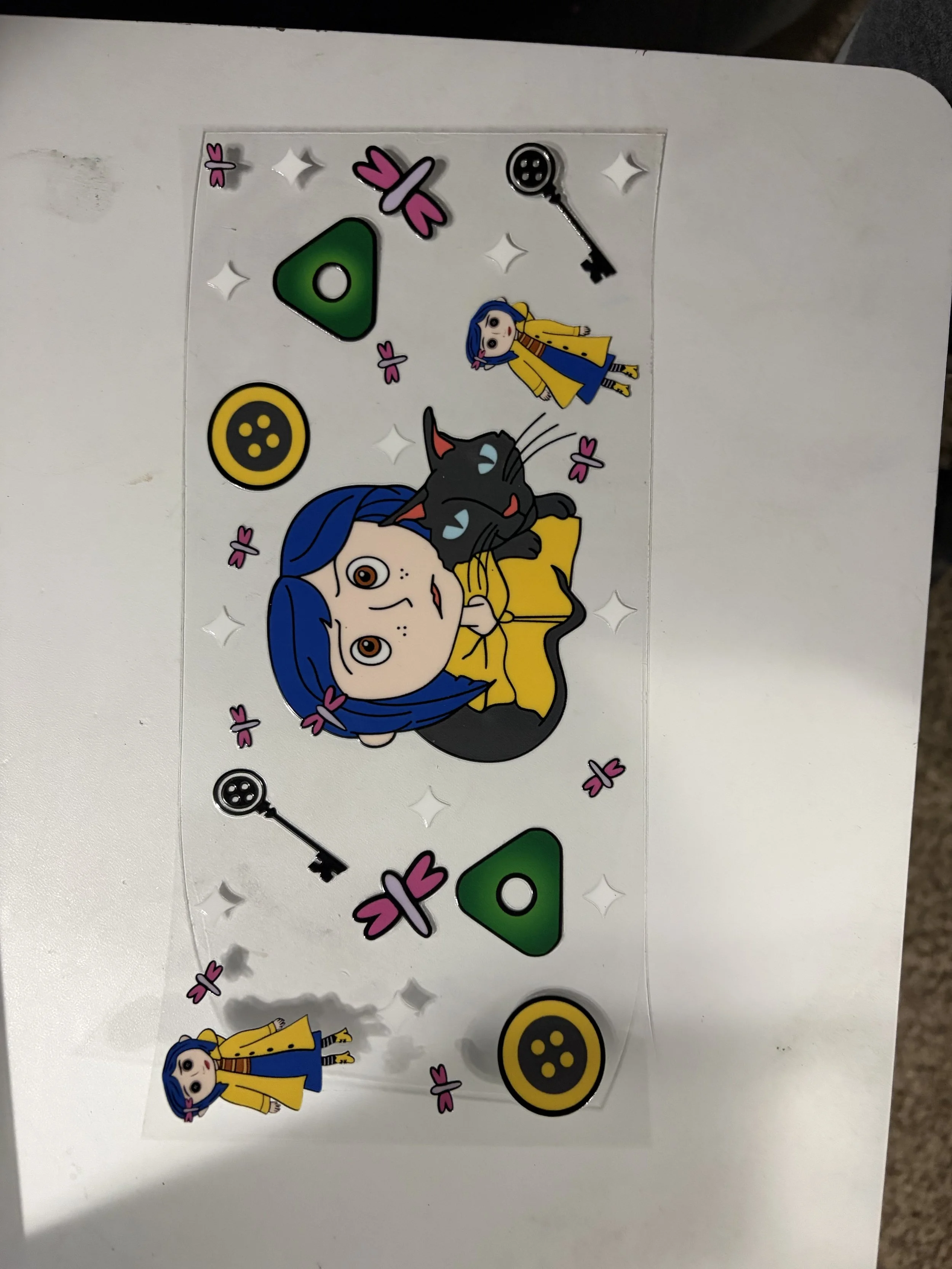 Decorative stickers on a white surface featuring cartoon characters, buttons, keys, flowers, and diamond shapes.