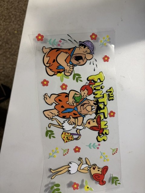 Sticker of the Flintstones characters with affectionate expressions and decorative flowers on a white surface.