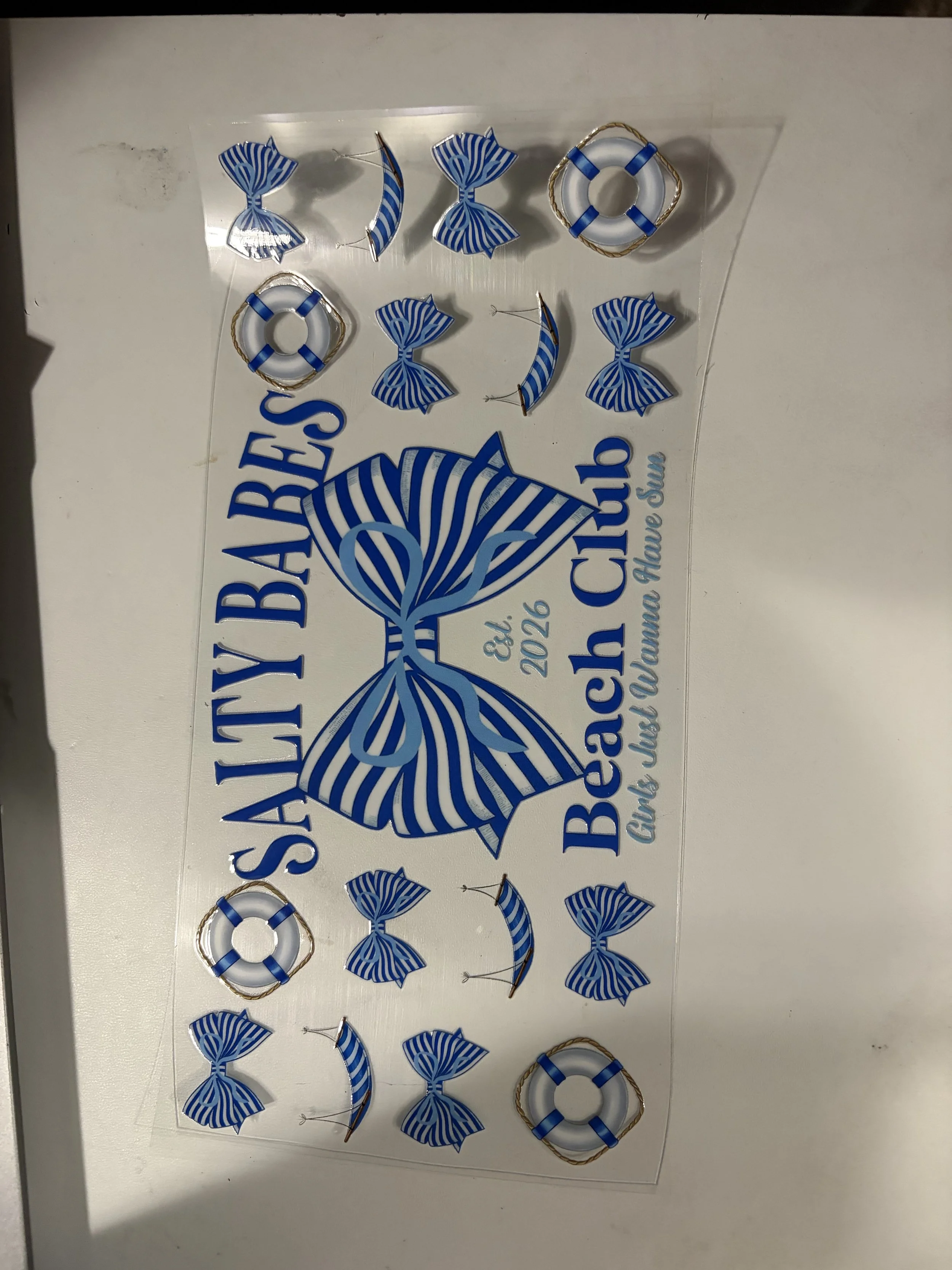A transparent sheet with blue and white striped candy-themed and life preserver-shaped decorations, along with blue text that reads 'SUBMARINES' and other smaller text.