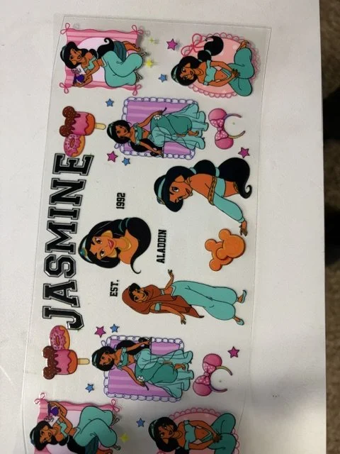 Sheet of stickers featuring a cartoon princess with long black hair, wearing different outfits and poses, along with stars, balloons, a cake, and the text 'JASMINE EST. ALL DAY 1992' in black and white.