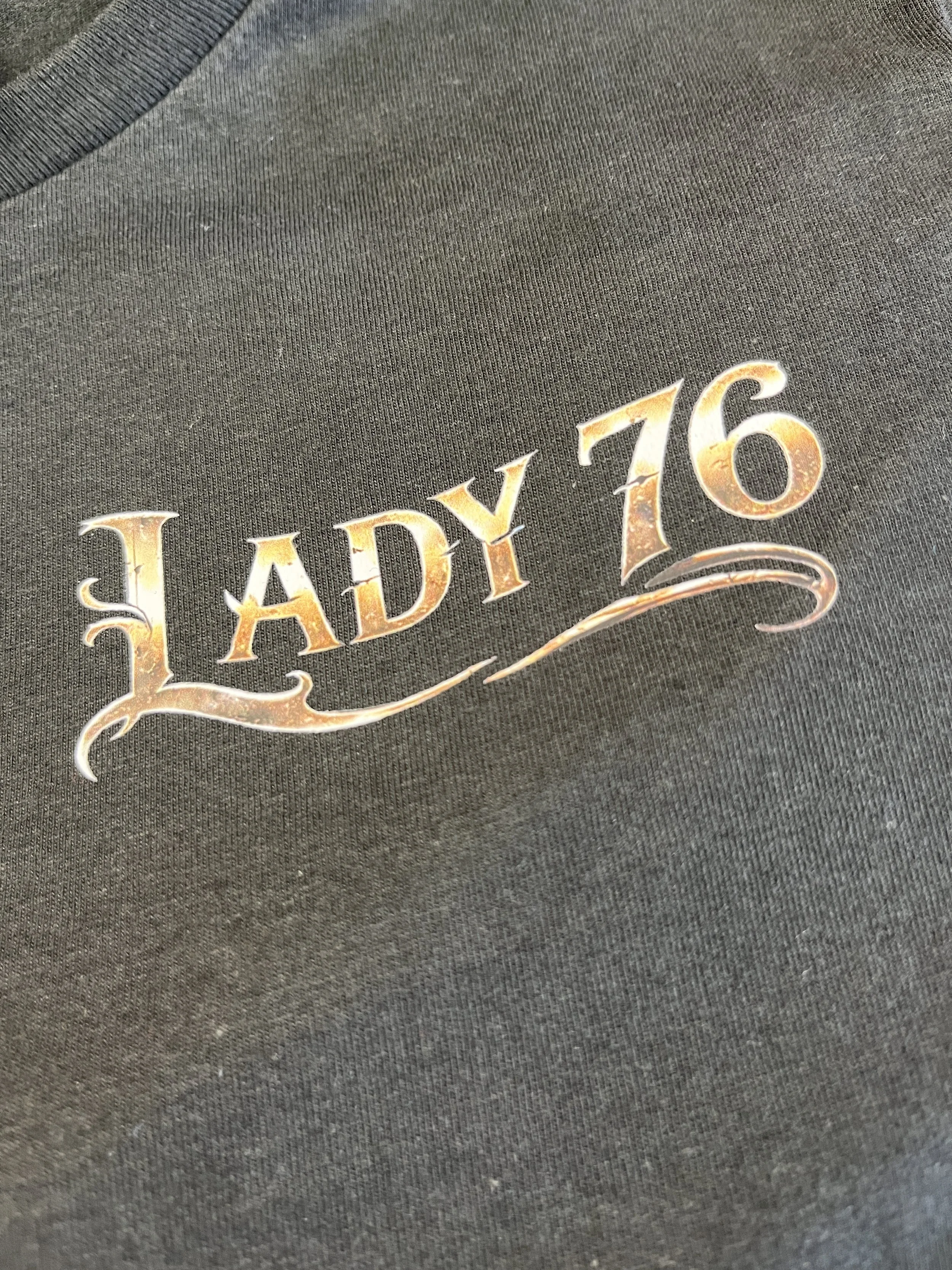 Close-up of black t-shirt with a Direct To Film DTF transfer logo that reads 'LADY 76'.