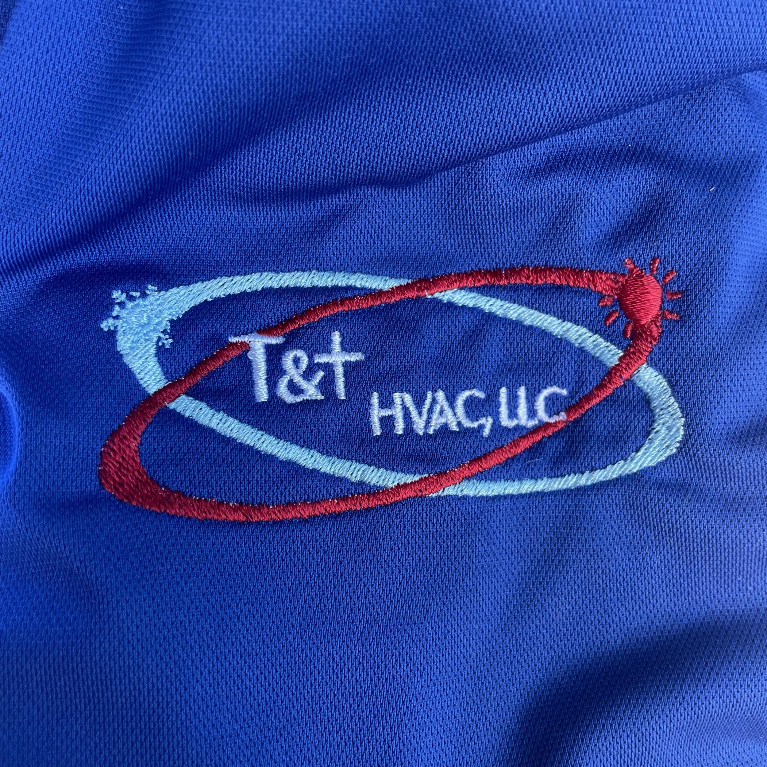 Close-up of embroidered T&T HVAC logo on blue fabric.