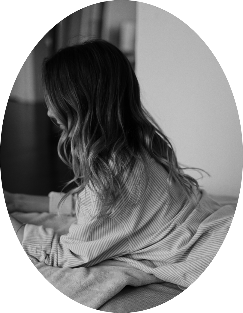 A woman with wavy hair reading or looking at something on a table in a room.