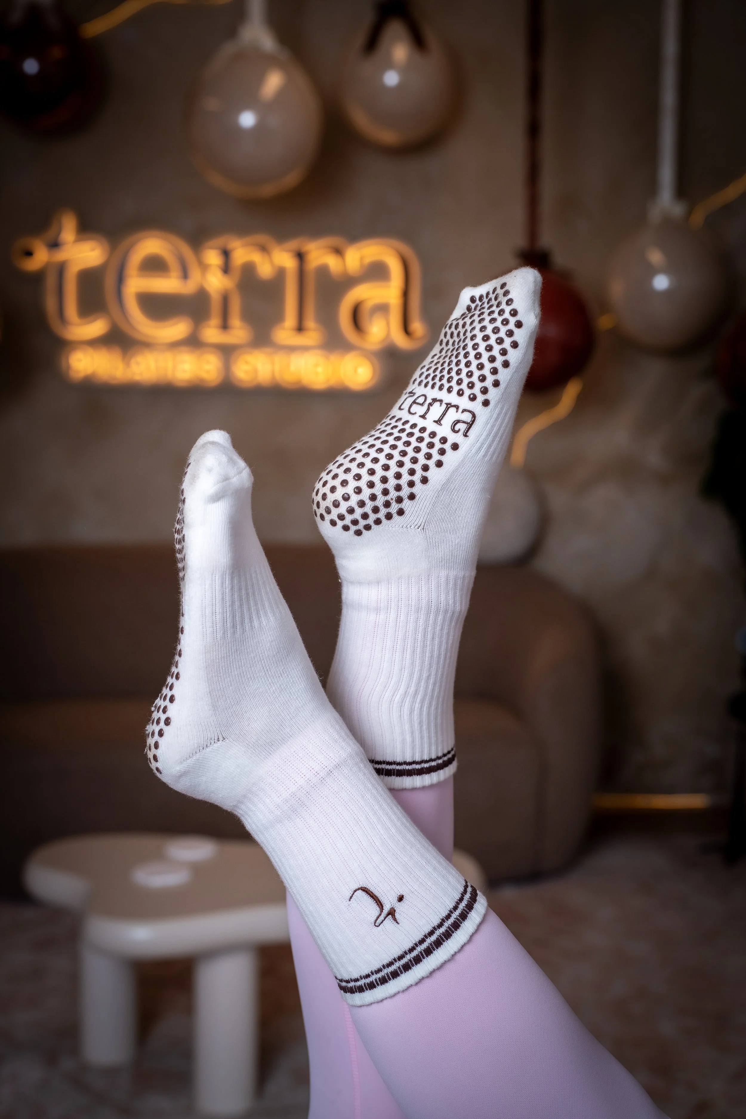 Manos con guantes blancos y detalles en negro, en un ambiente decorado con globos y luces, con un letrero de neón que dice 'tierra' y 'el arte está en ti'.