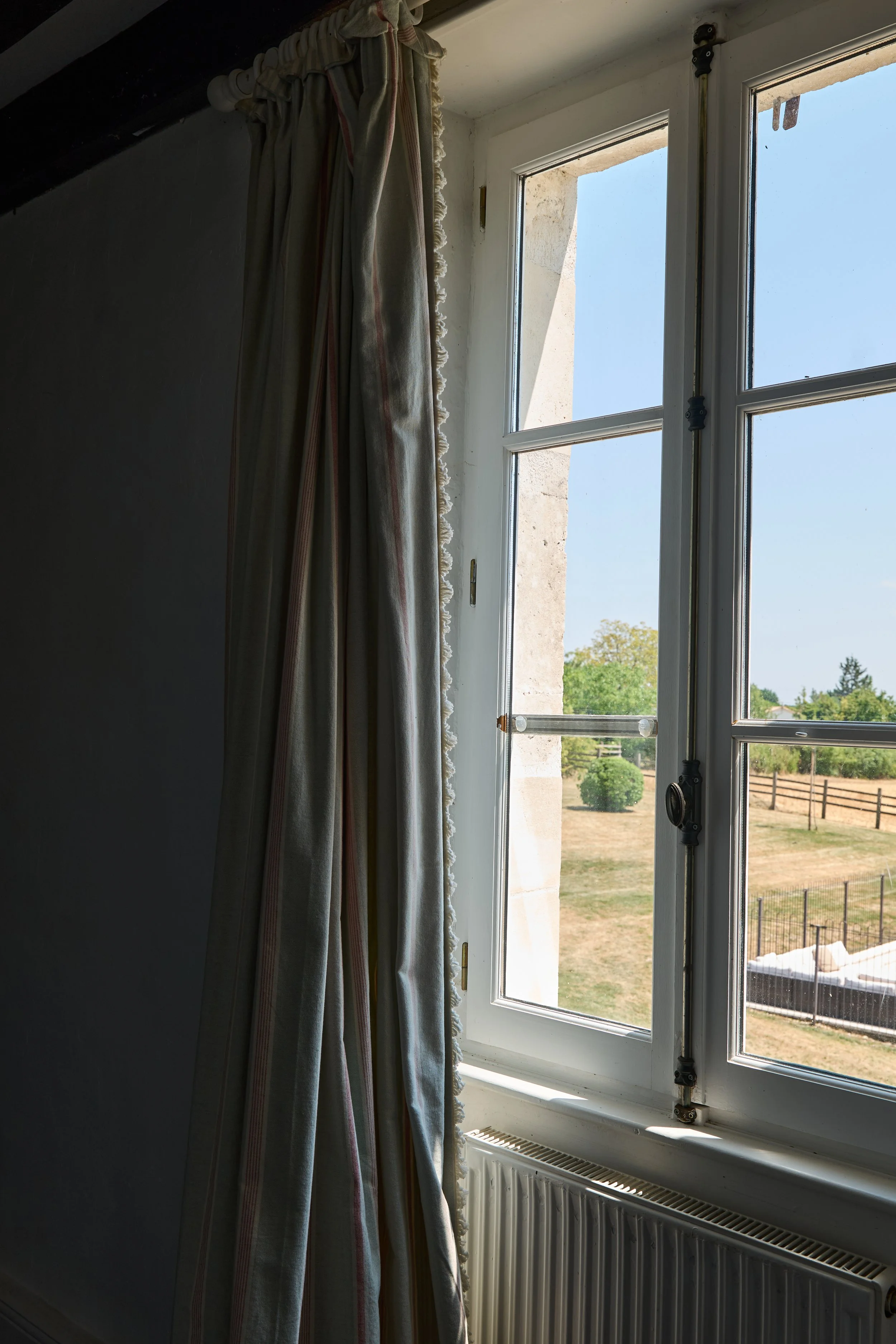 View through a window showing a clear sky with a hint of trees and a fenced outdoor area