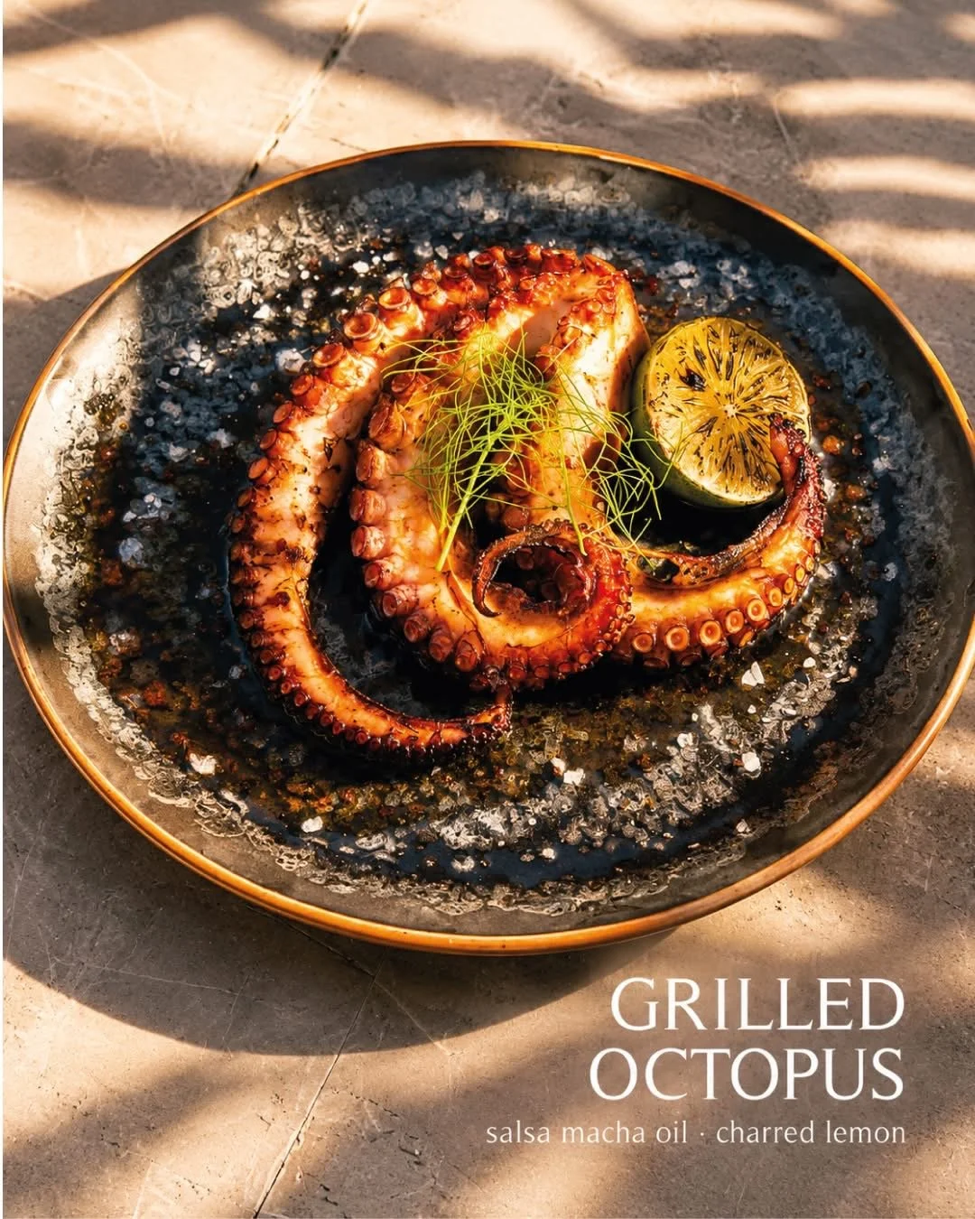 Grilled octopus tentacles garnished with lemon and herbs on a plate